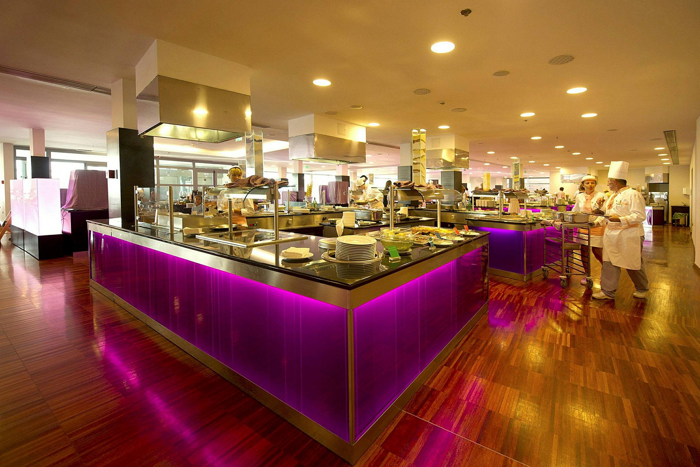 Bilde av en restaurant eller buffetområde med moderne og fargerike interiørdetaljer, inkludert lys lilla belysning under diskene. (AI-generert tekst)