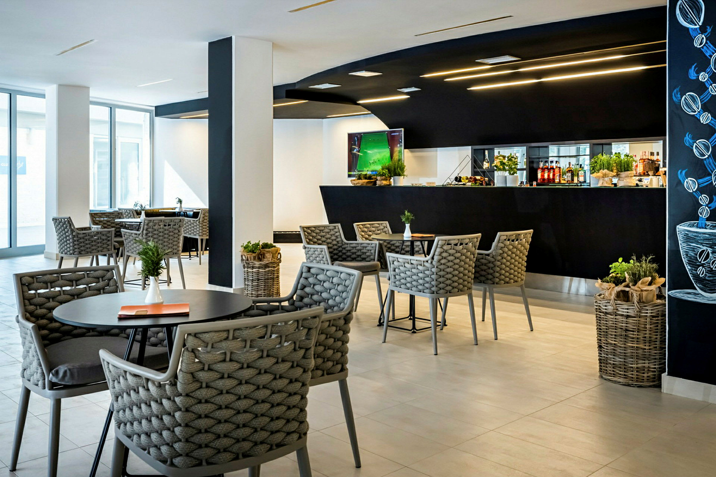 Et moderne kafé med bord og stoler samt en svart bardisk i bakgrunnen. (AI-generert tekst)