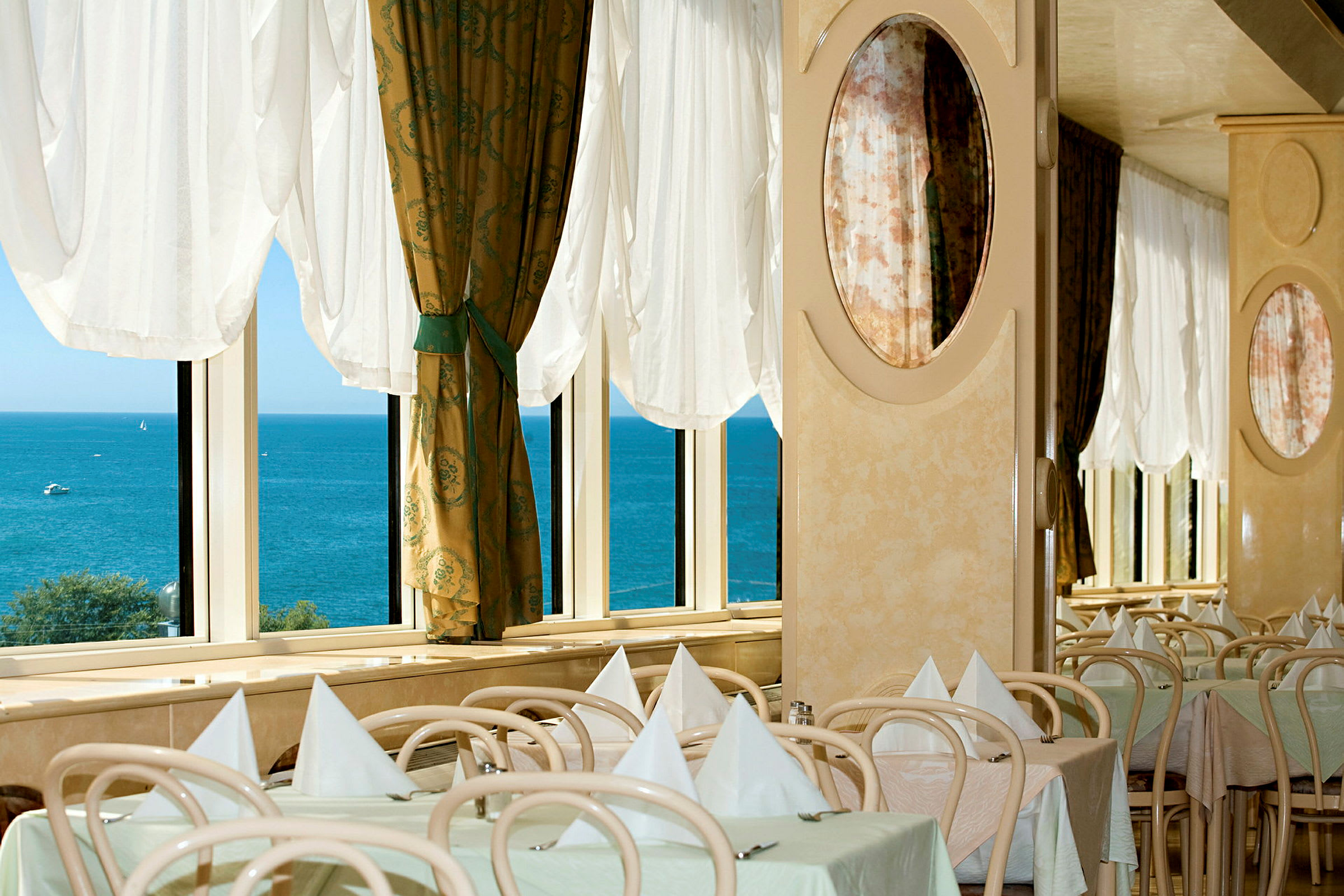 Restaurant med dekkede bord ved vinduene med utsikt over havet. (AI-generert tekst)