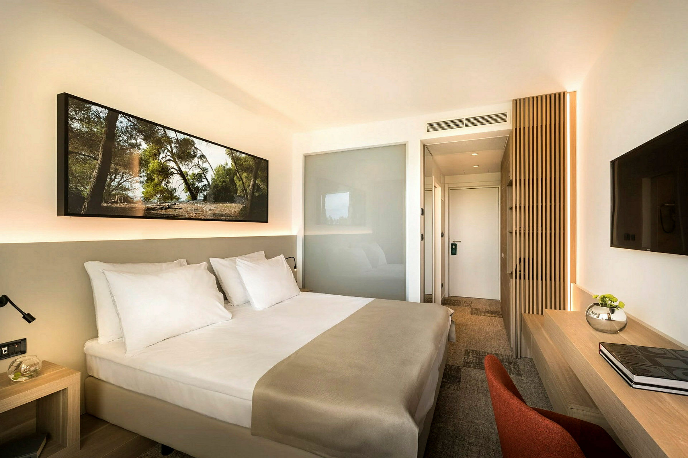 Hotellrom med en dobbeltseng, et skrivebord og en TV på veggen. (AI-generert tekst)