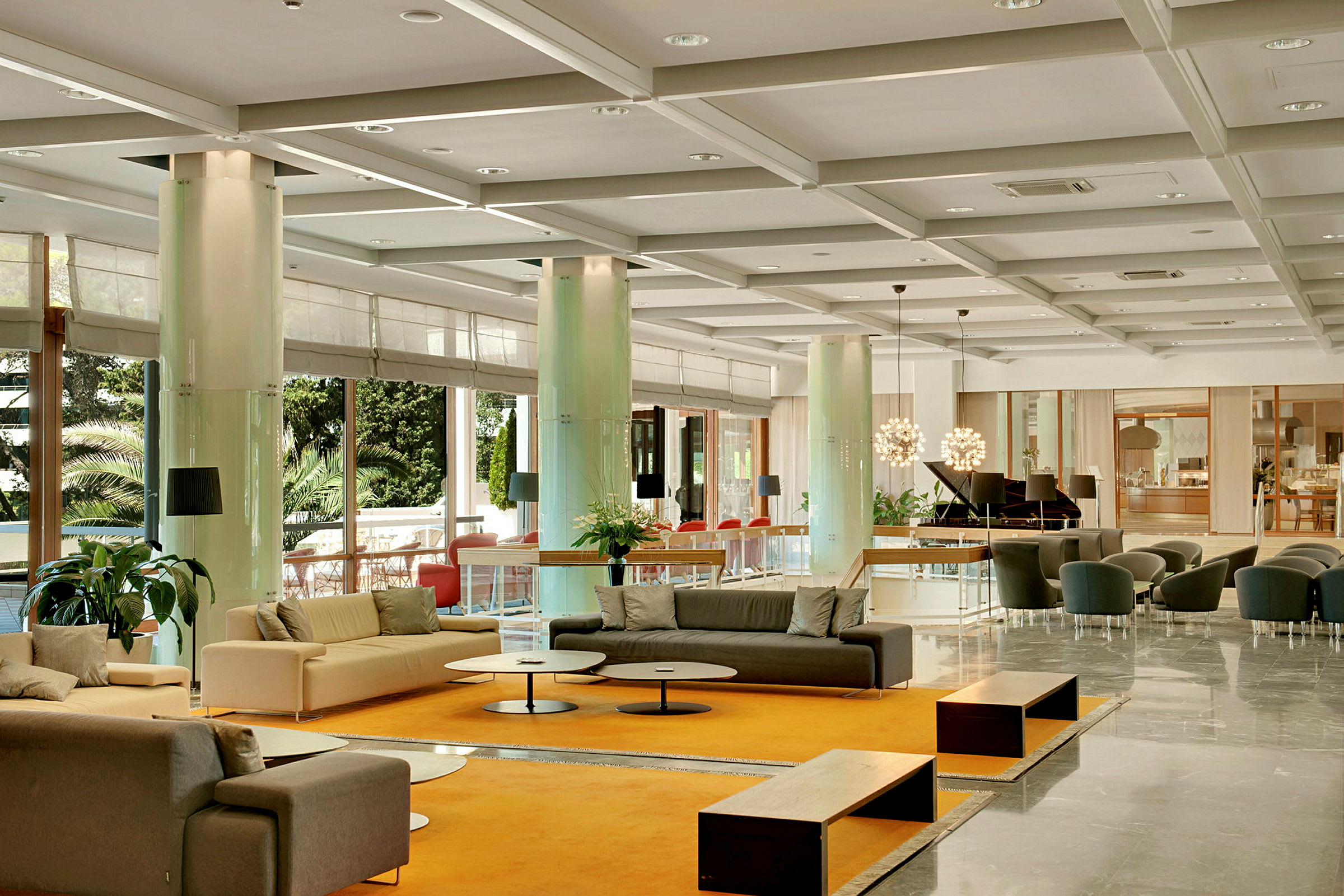 En lys og romslig hotellobby med sofaer, bord og dekorative planter. (AI-generert tekst)