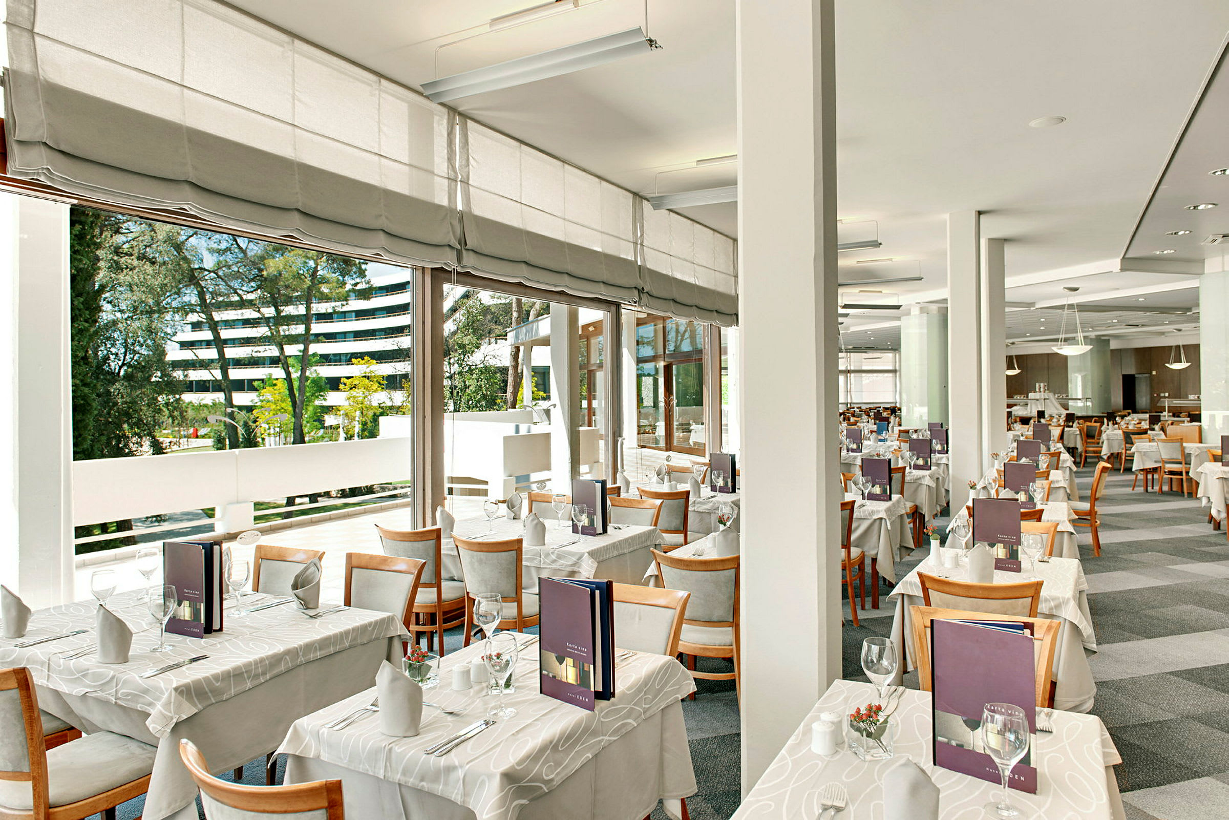 Moderne og lys restaurantområde med dekkede bord og store vinduer. (AI-generert tekst)