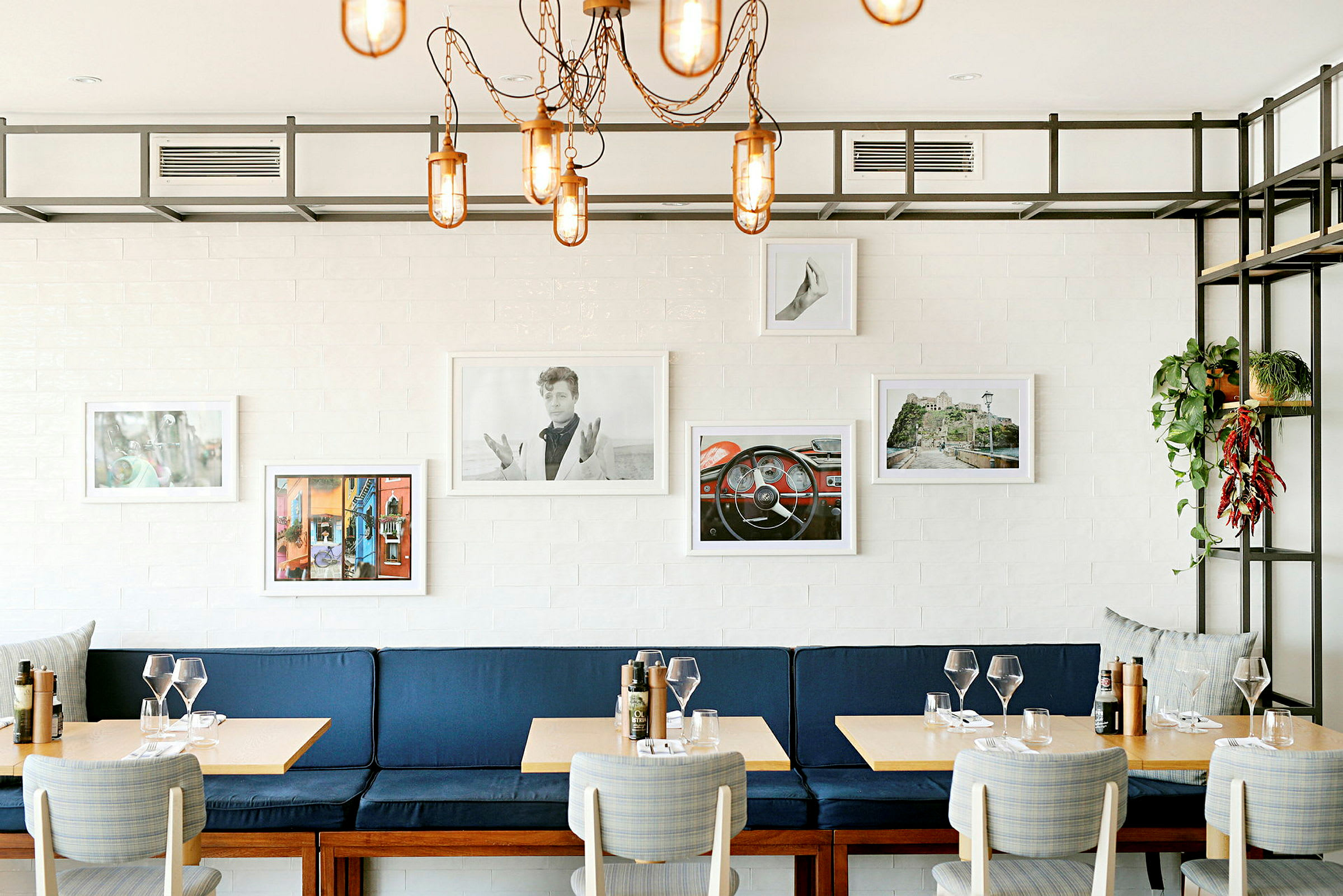En restaurant med blå benk, trebord og dekorative bilder på veggen. (AI-generert tekst)