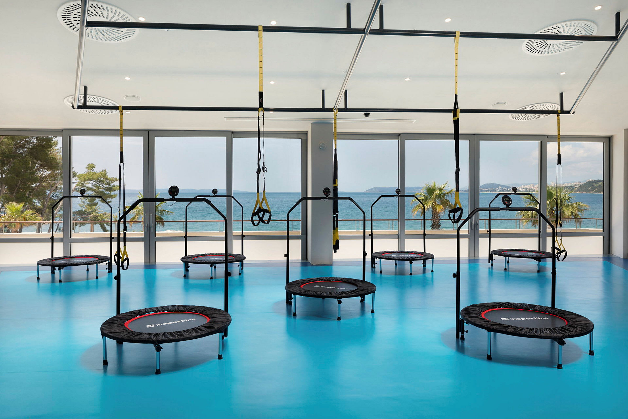Gym med trampoliner og treningsutstyr, med havutsikt. (AI-generert tekst)
