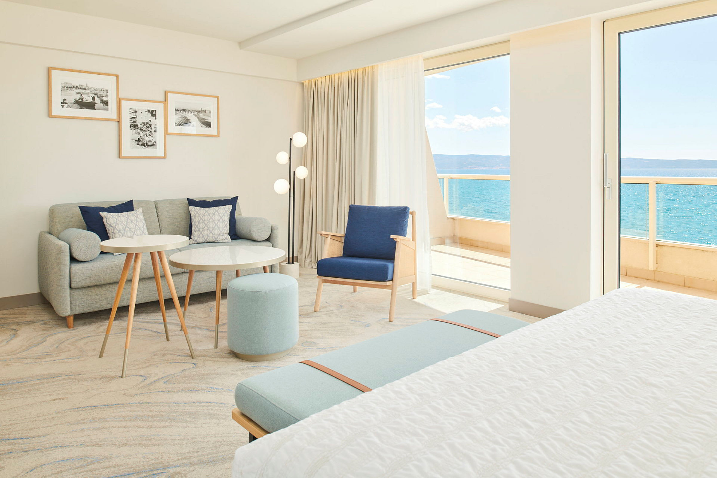 Lyst og moderne hotellrom med sittegruppe og utsikt mot havet. (AI-generert tekst)