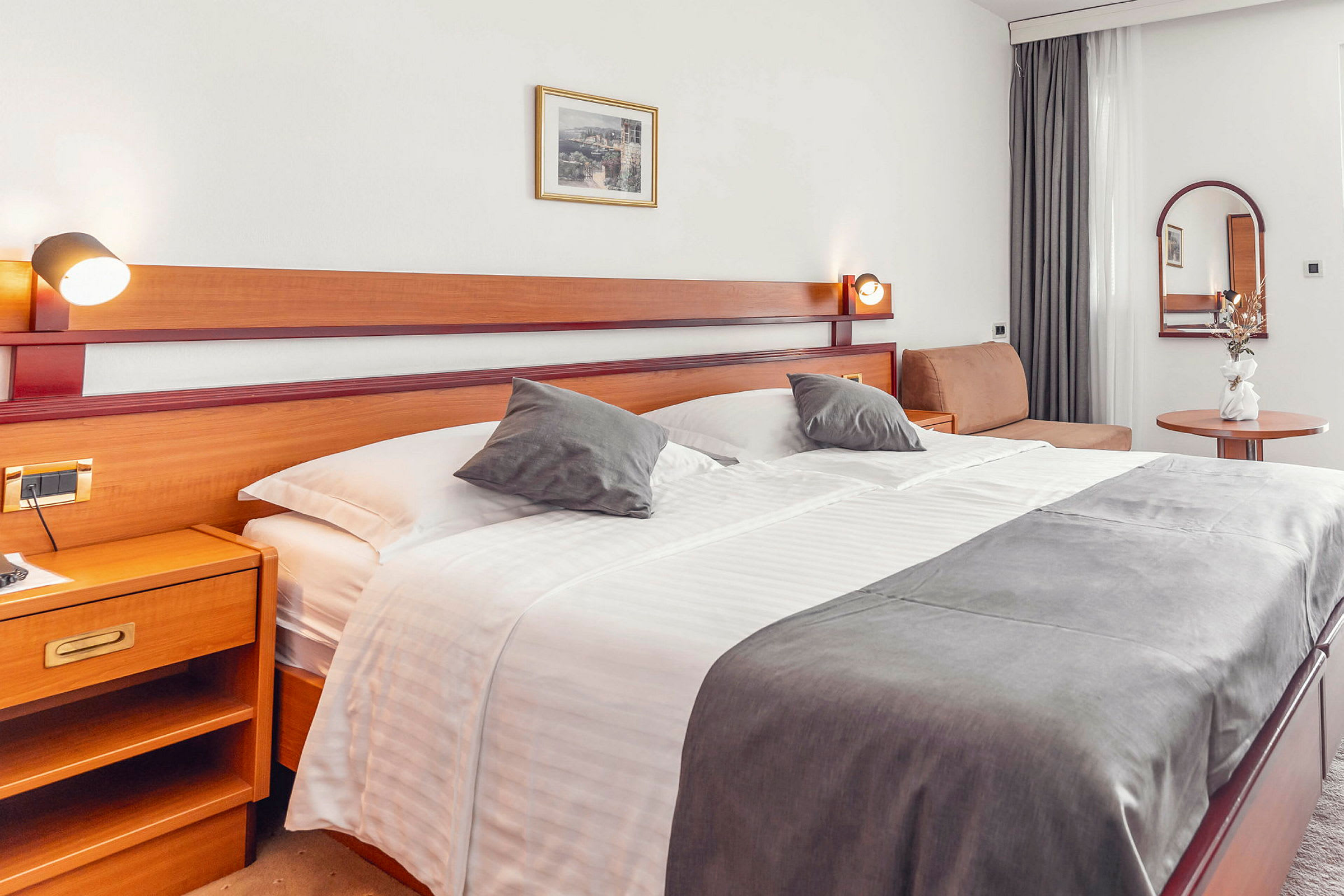Hotellrom med stor seng, sidebord og dekorasjoner. (AI-generert tekst)