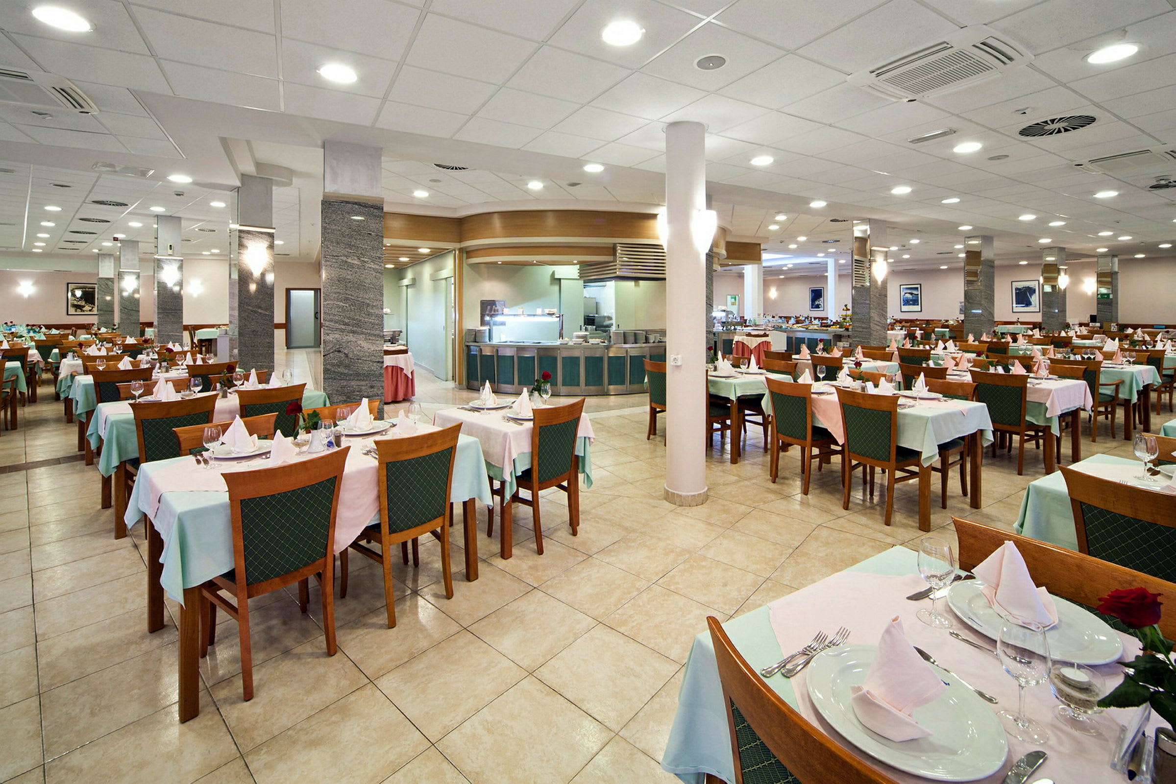 En restaurant med dekkede bord og stoler, tom og opplyst. (AI-generert tekst)