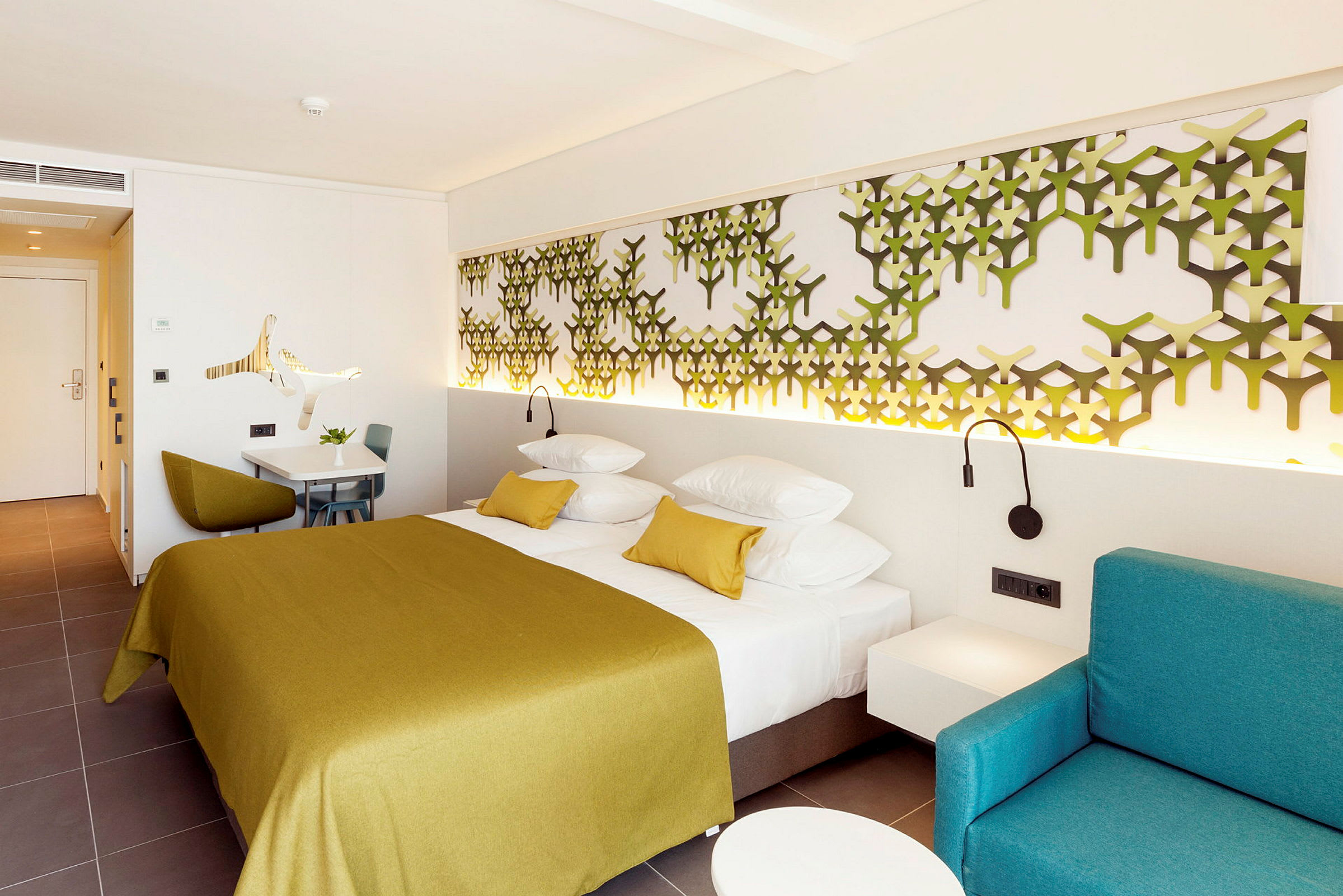 Et moderne hotellrom med en dobbeltseng, veggdekorasjon og en sittegruppe. (AI-generert tekst)