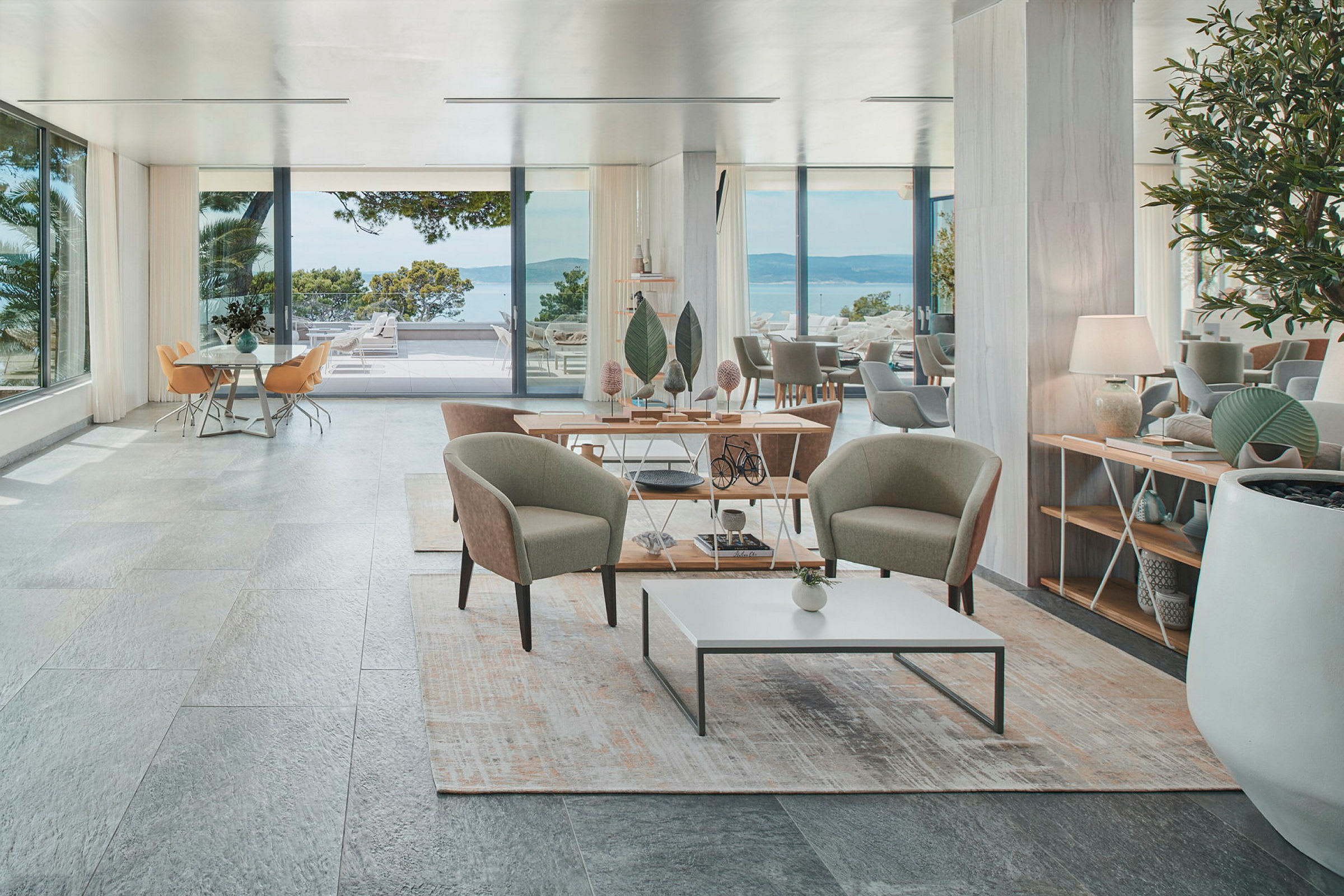 Et elegant hotellrom med sittegruppe, store vinduer og utsikt mot havet. (AI-generert tekst)