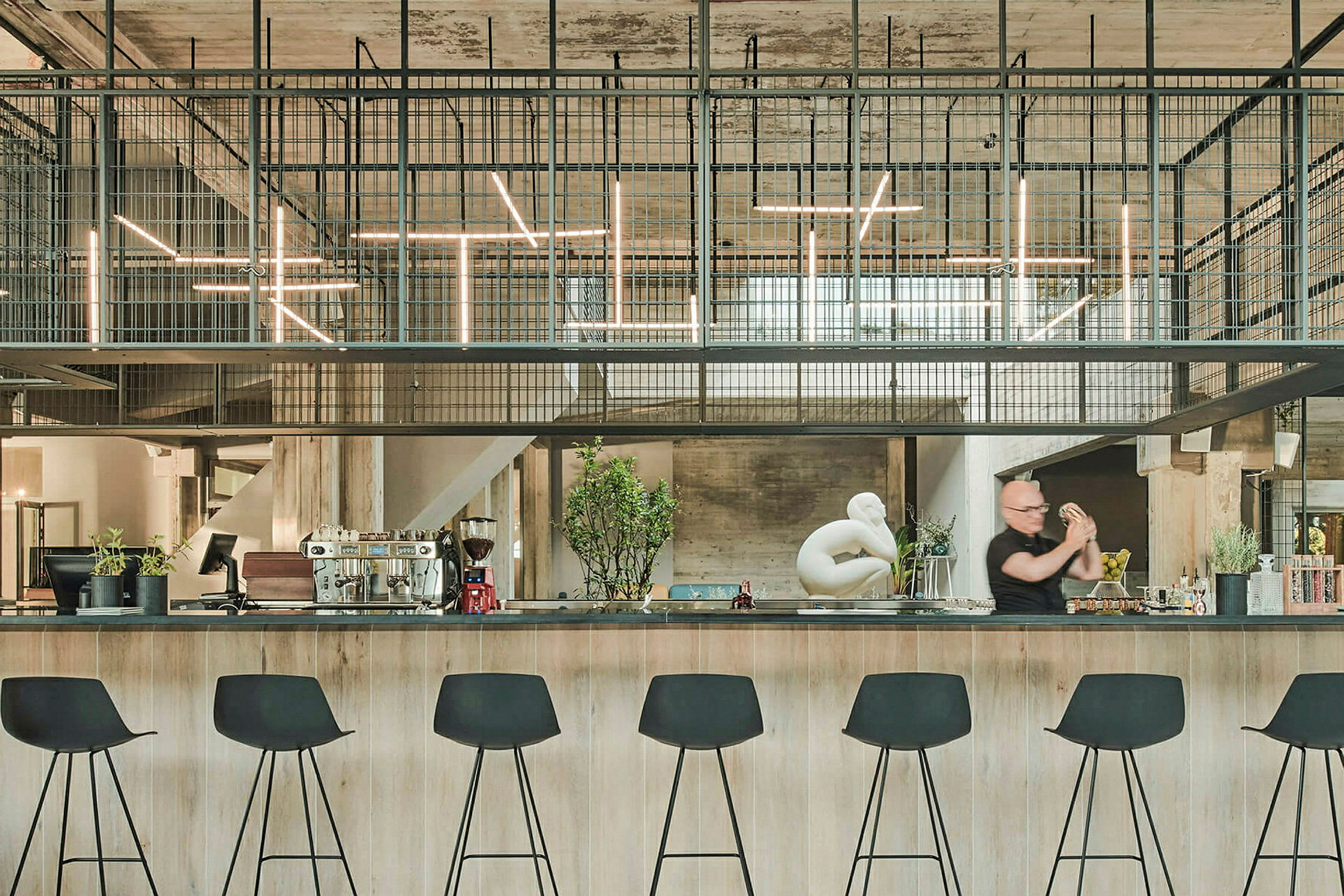 En moderne bar med høye svarte stoler og industriell innredning. (AI-generert tekst)