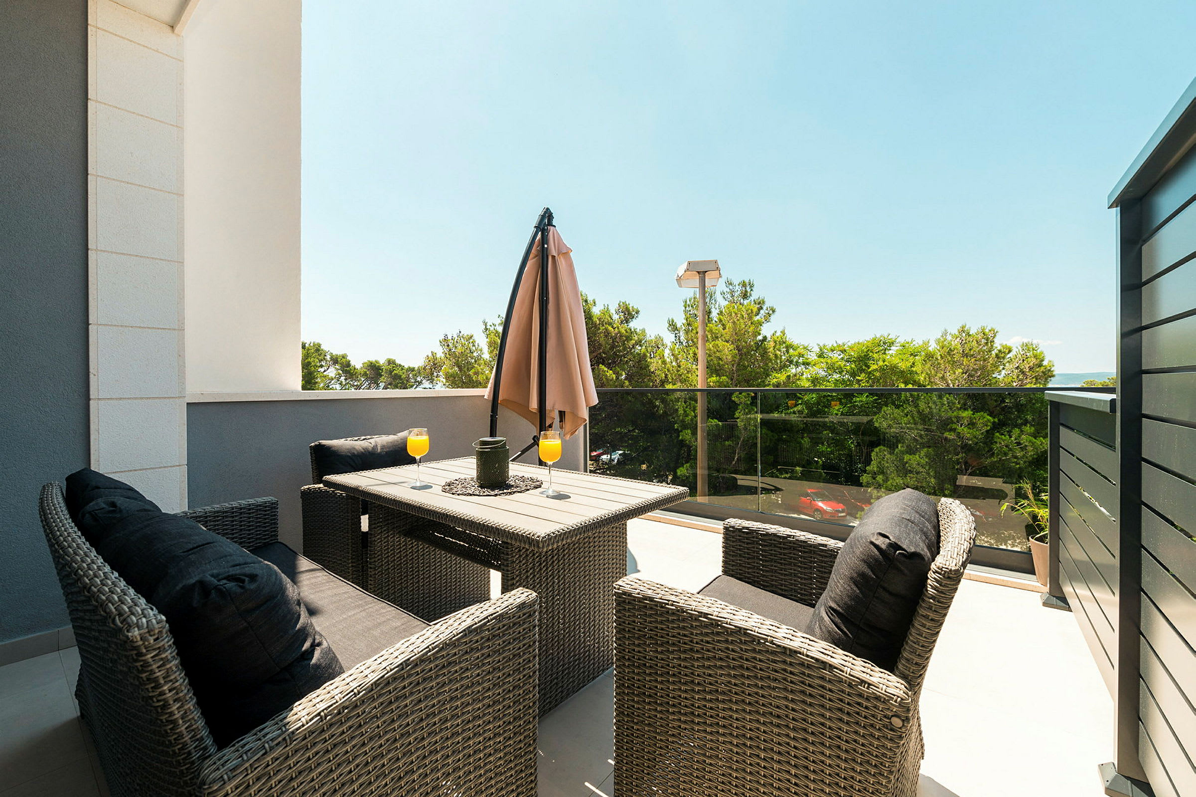 En terrasse med sittegruppe og to glass appelsinjuice på bordet. (AI-generert tekst)