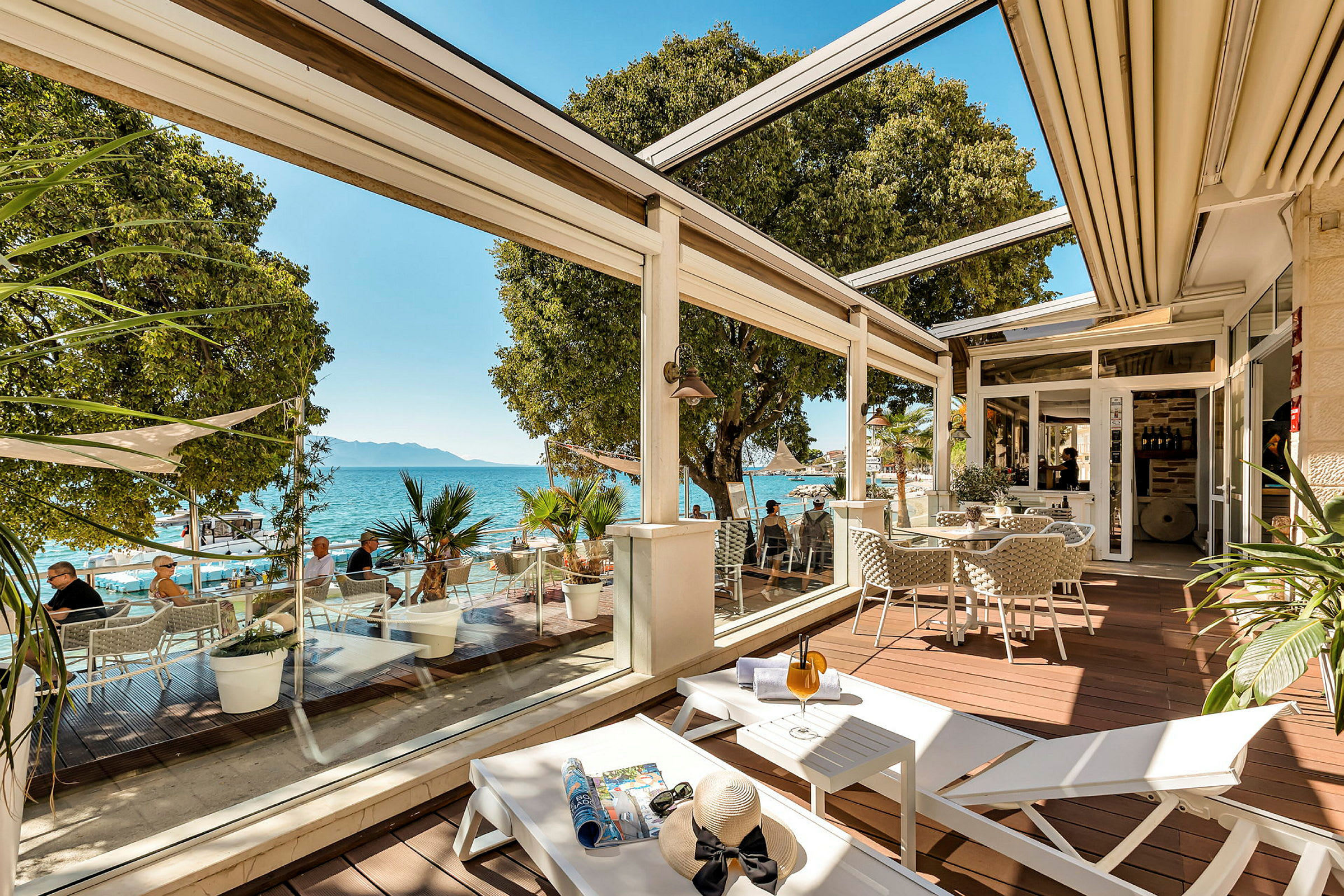 En terrasse med sitteplasser, solsenger og utsikt over havet. (AI-generert tekst)