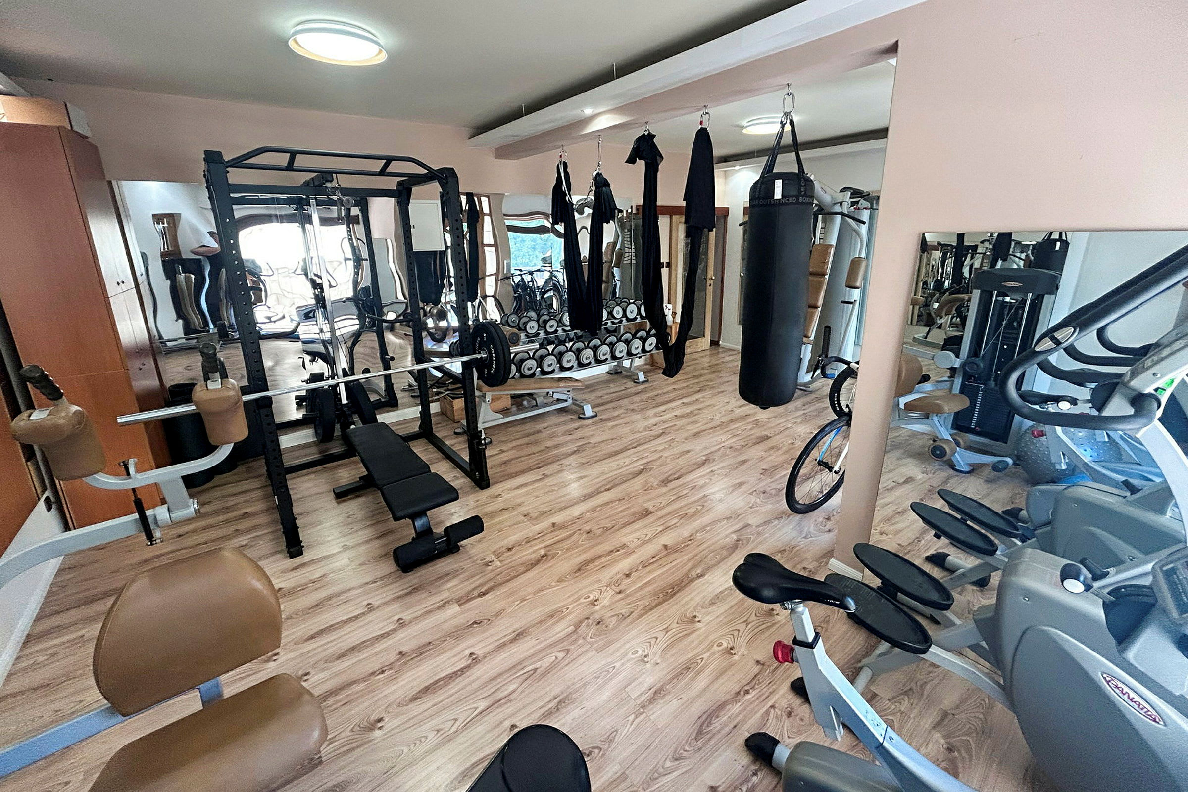 Bilde av et treningsstudio med treningsutstyr som vekter, tredemøller og punching bag. (AI-generert tekst)