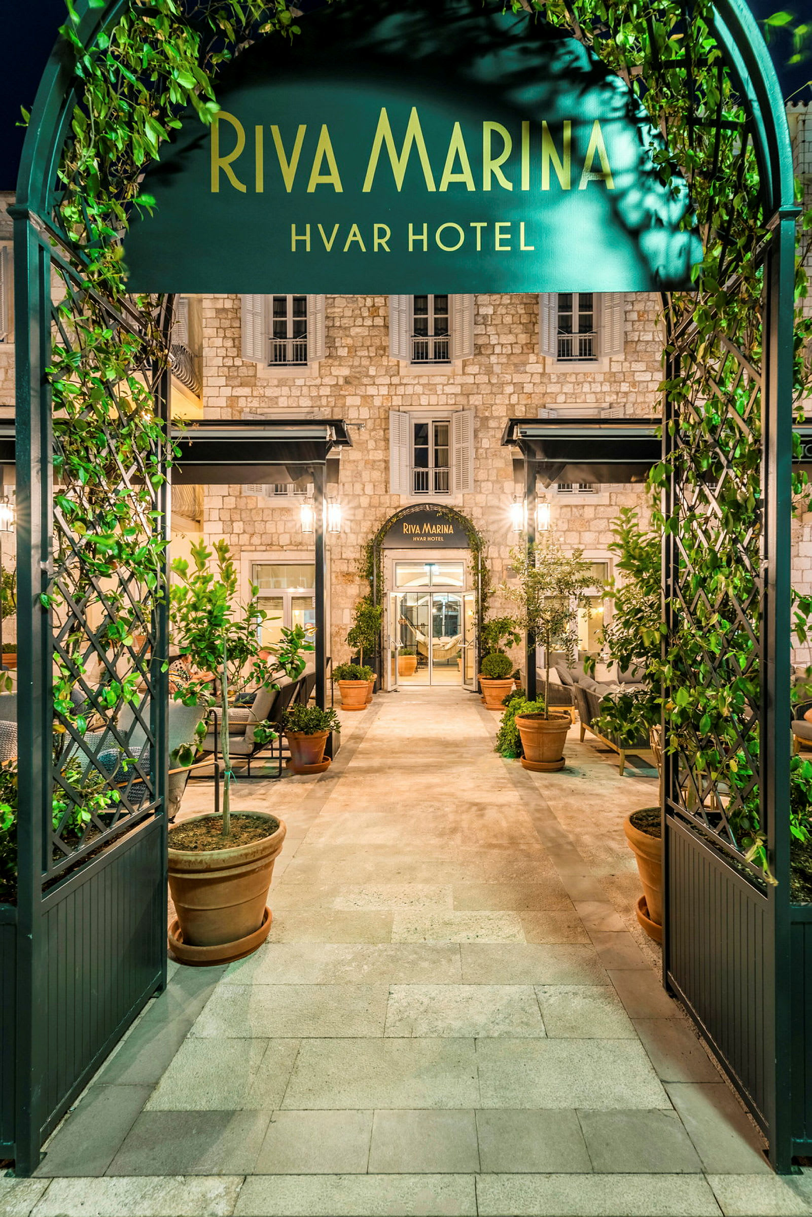 Inngang til Riva Marina Hvar Hotel, med frodige planter og elegant arkitektur. (AI-generert tekst)