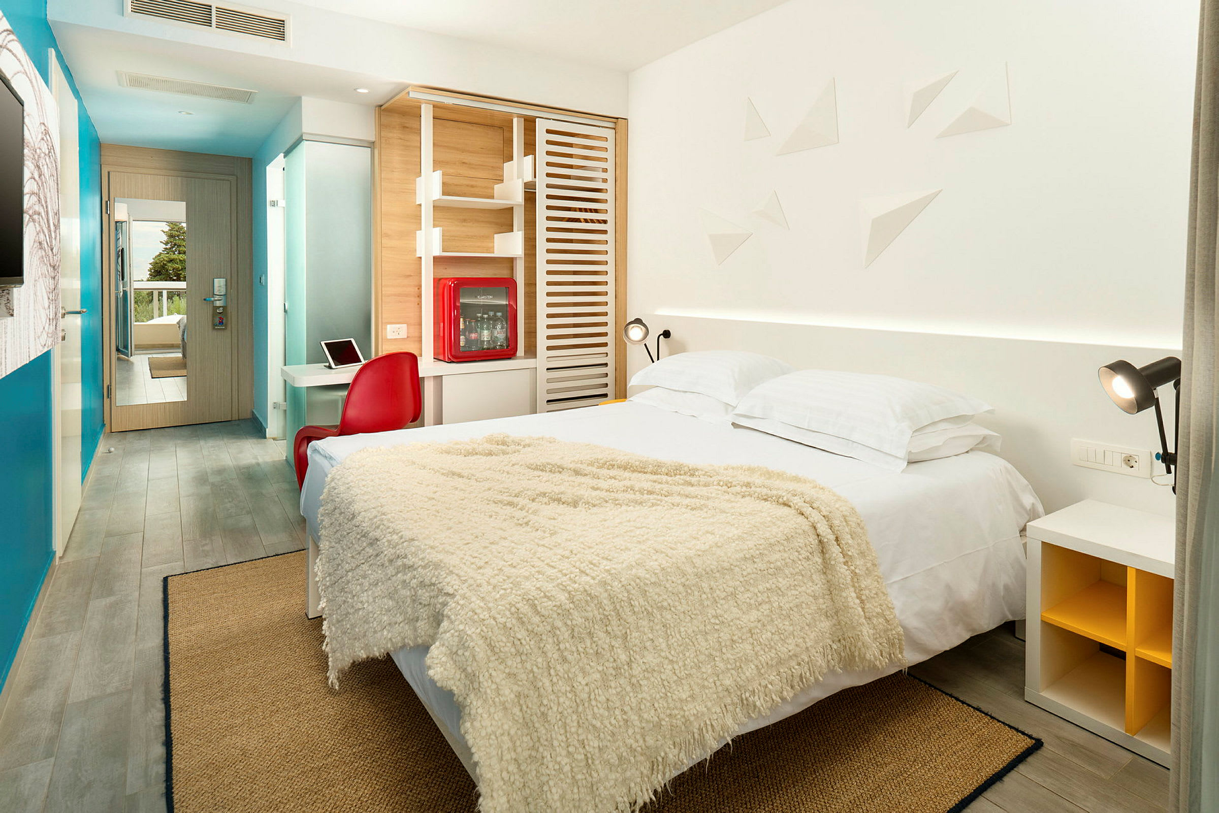 Et moderne innredet hotellrom med en dobbeltseng, fargerike dekorasjoner og et skrivebord. (AI-generert tekst)