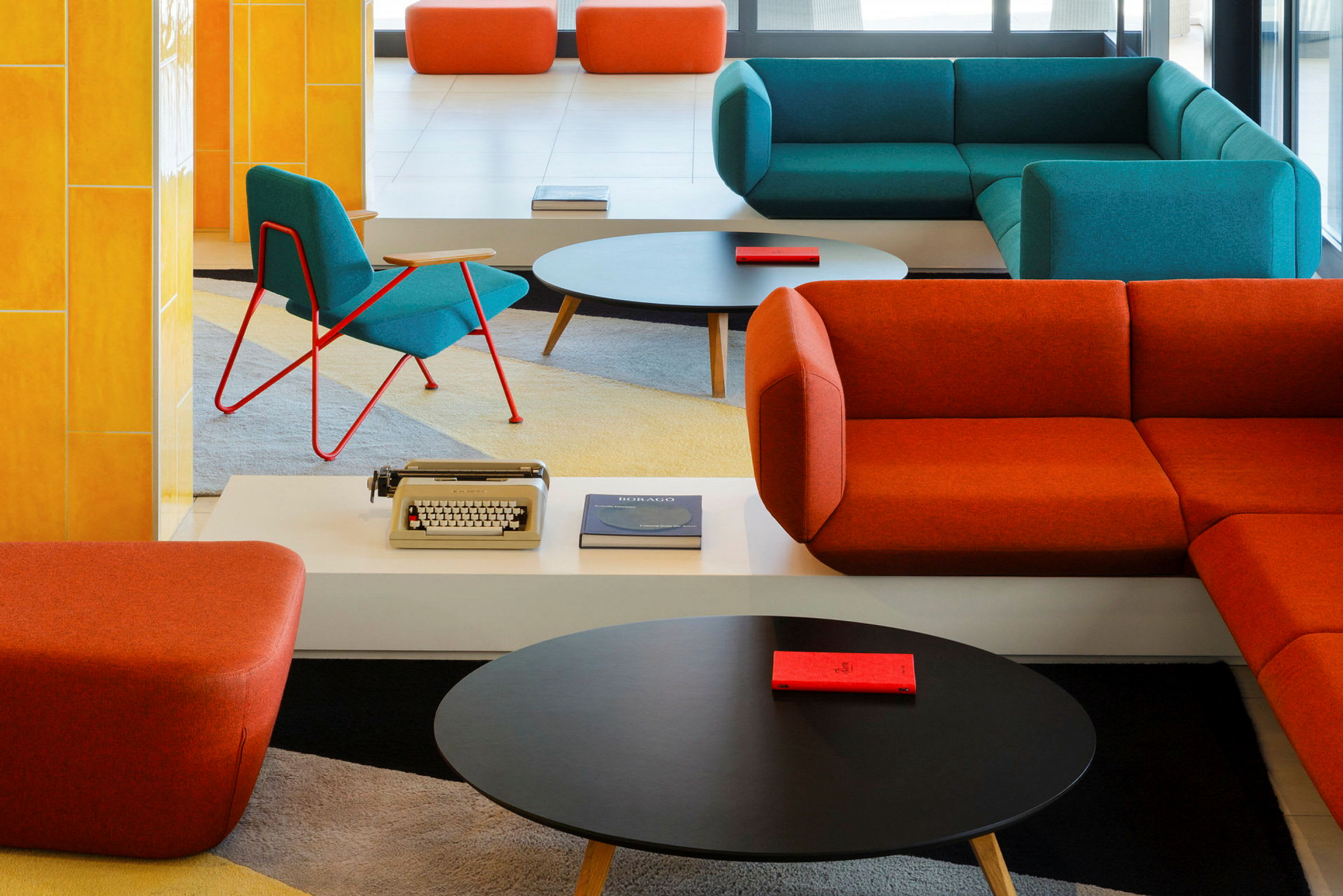 Interiørbilde av en moderne lounge med fargerike sofaer og stoler, et salongbord og dekorative elementer. (AI-generert tekst)