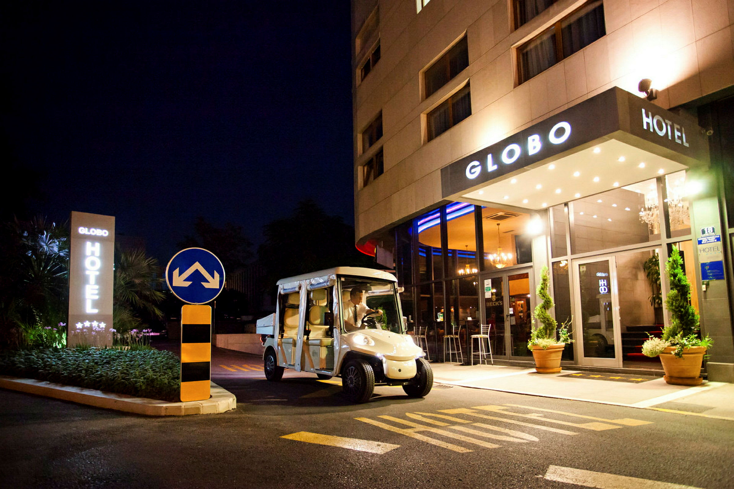 Et hotell sett om natten med navnet Globo, en elbil er parkert foran inngangen. (AI-generert tekst)