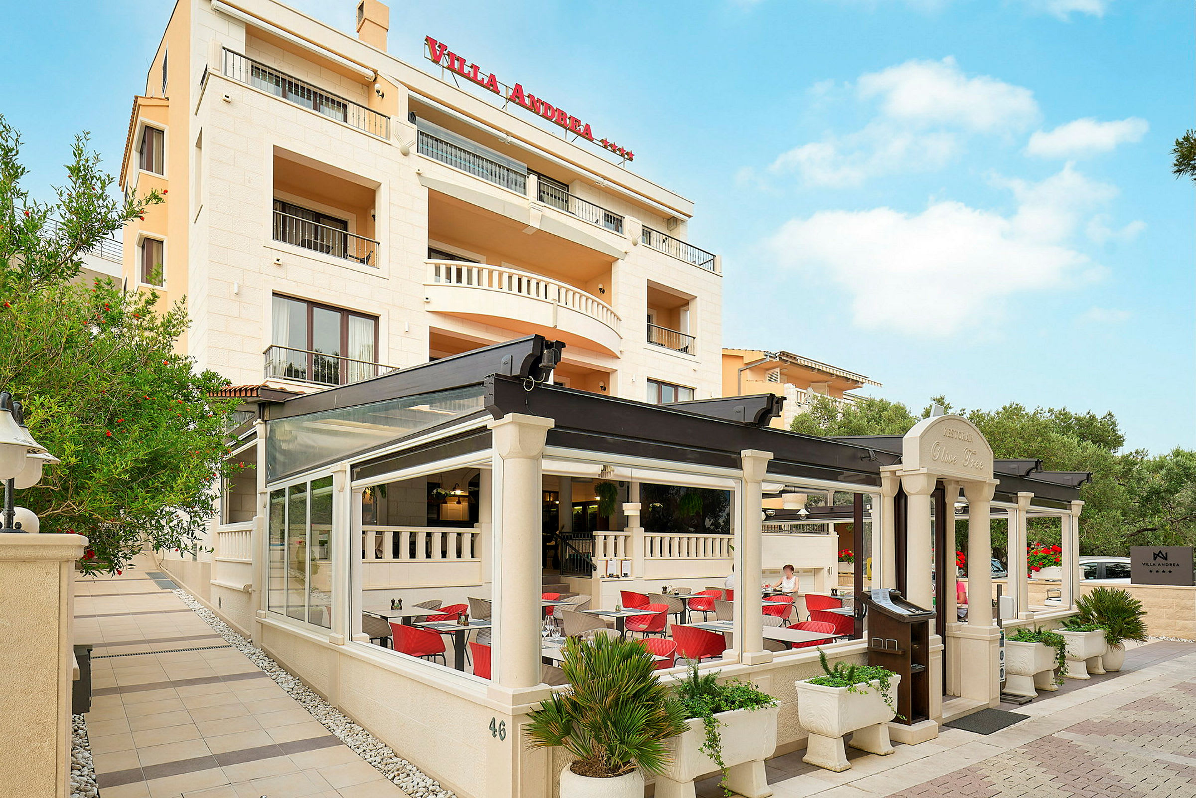 Fasaden til Villa Andrea hotell med en utestaurant. (AI-generert tekst)