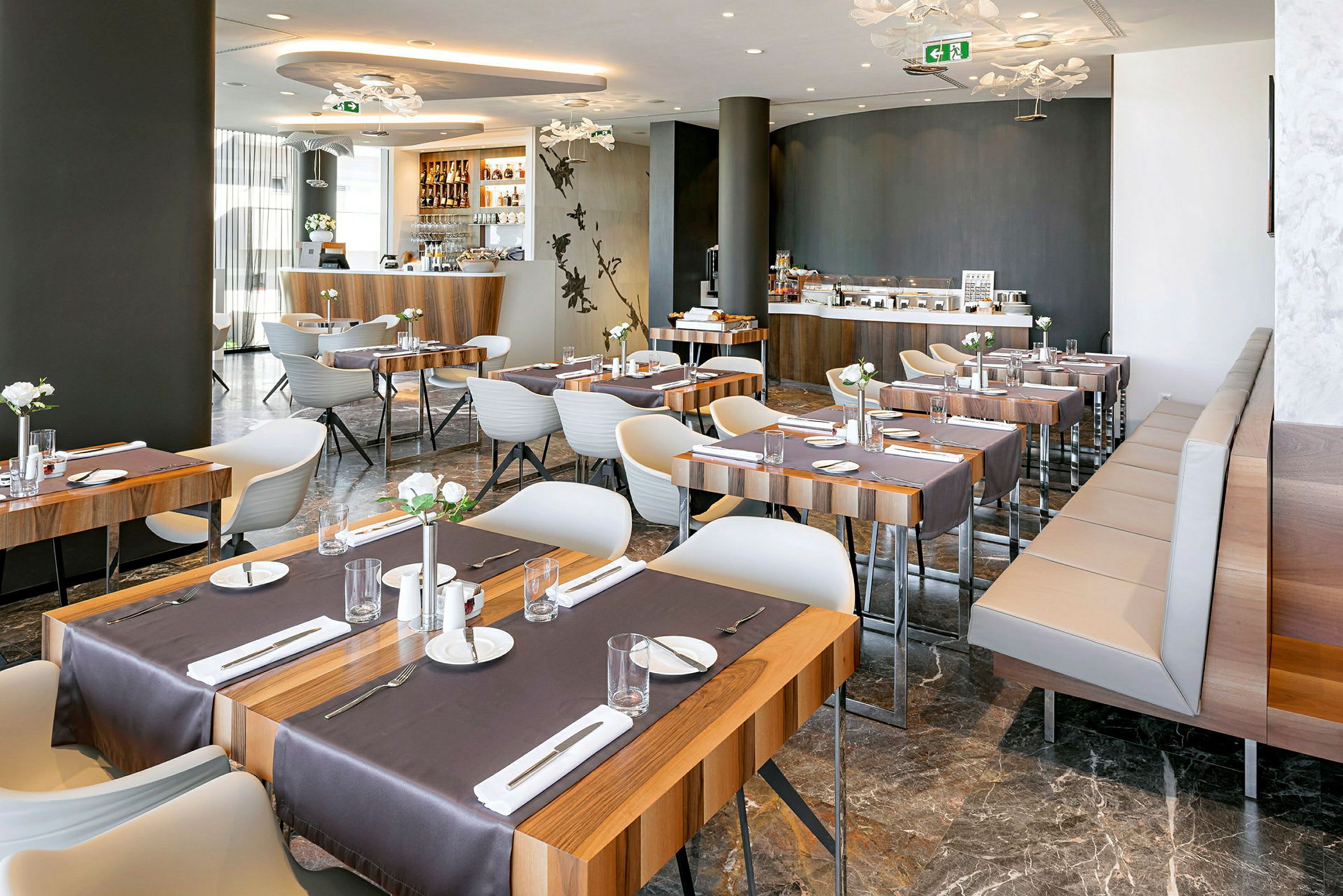 Et moderne restaurantområde med trebord og hvite stoler, dekket til måltider. (AI-generert tekst)
