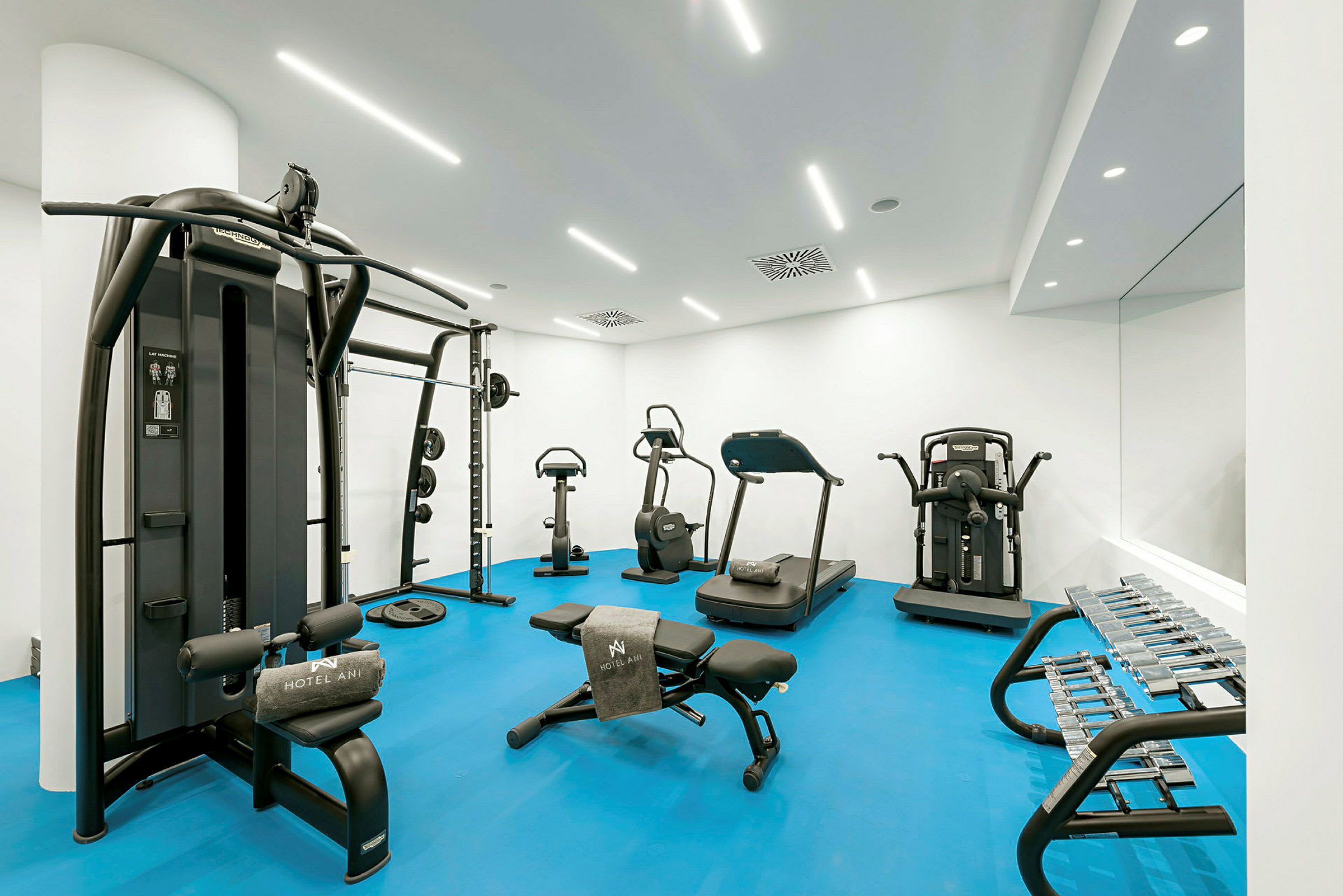 Treningsstudio med treningsutstyr, inkludert tredemølle, trimsykler og dumbbells. (AI-generert tekst)