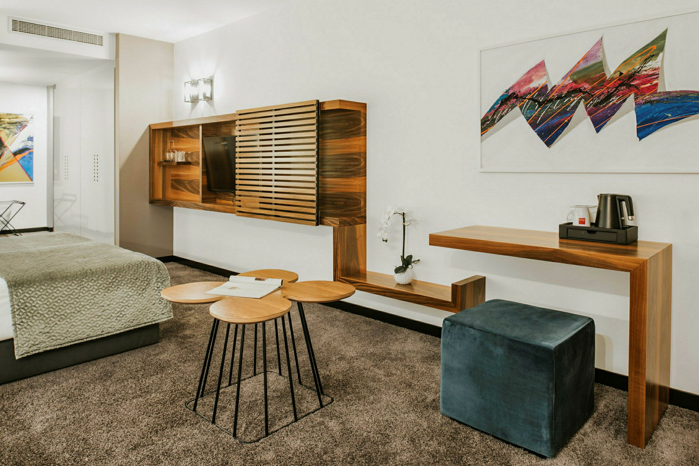 Et moderne hotellrom med tremøbler, en sittepuff og kunst på veggen. (AI-generert tekst)