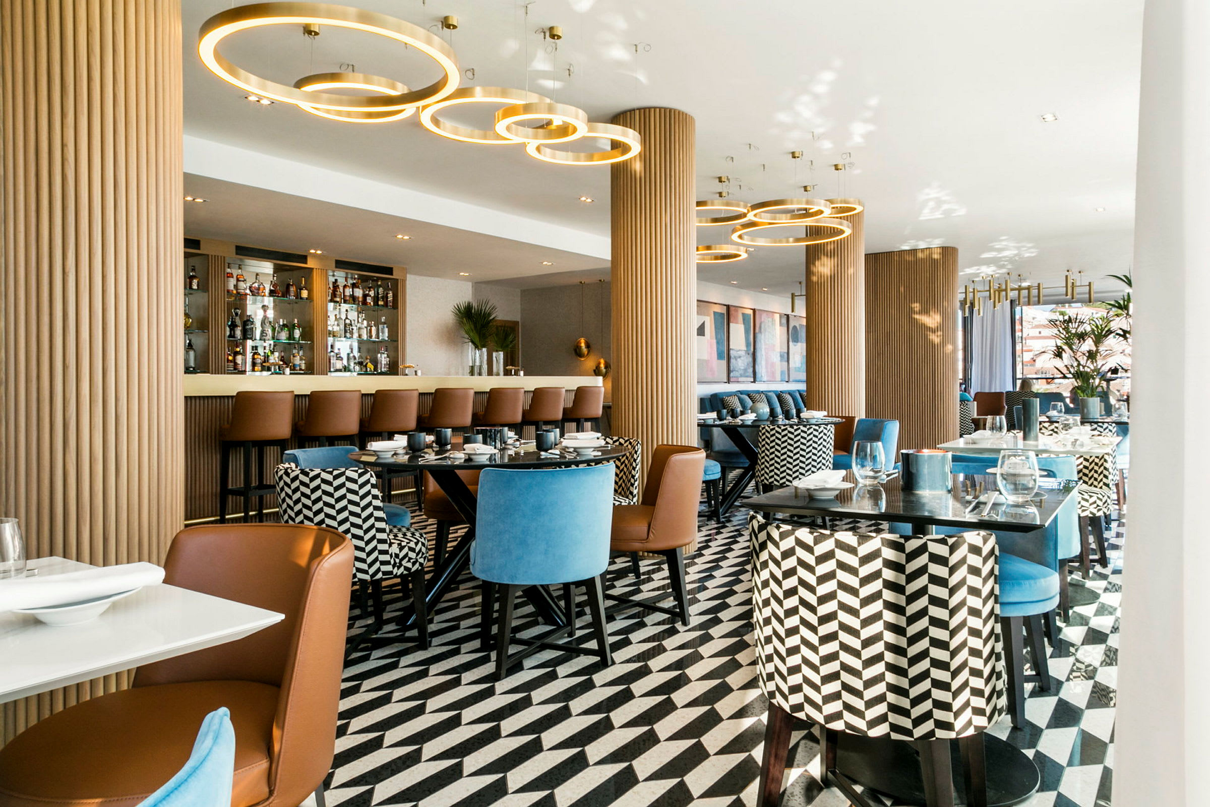 En elegant restaurant med moderne sittemøbler, et mønstret gulv og en bardisk i bakgrunnen. (AI-generert tekst)