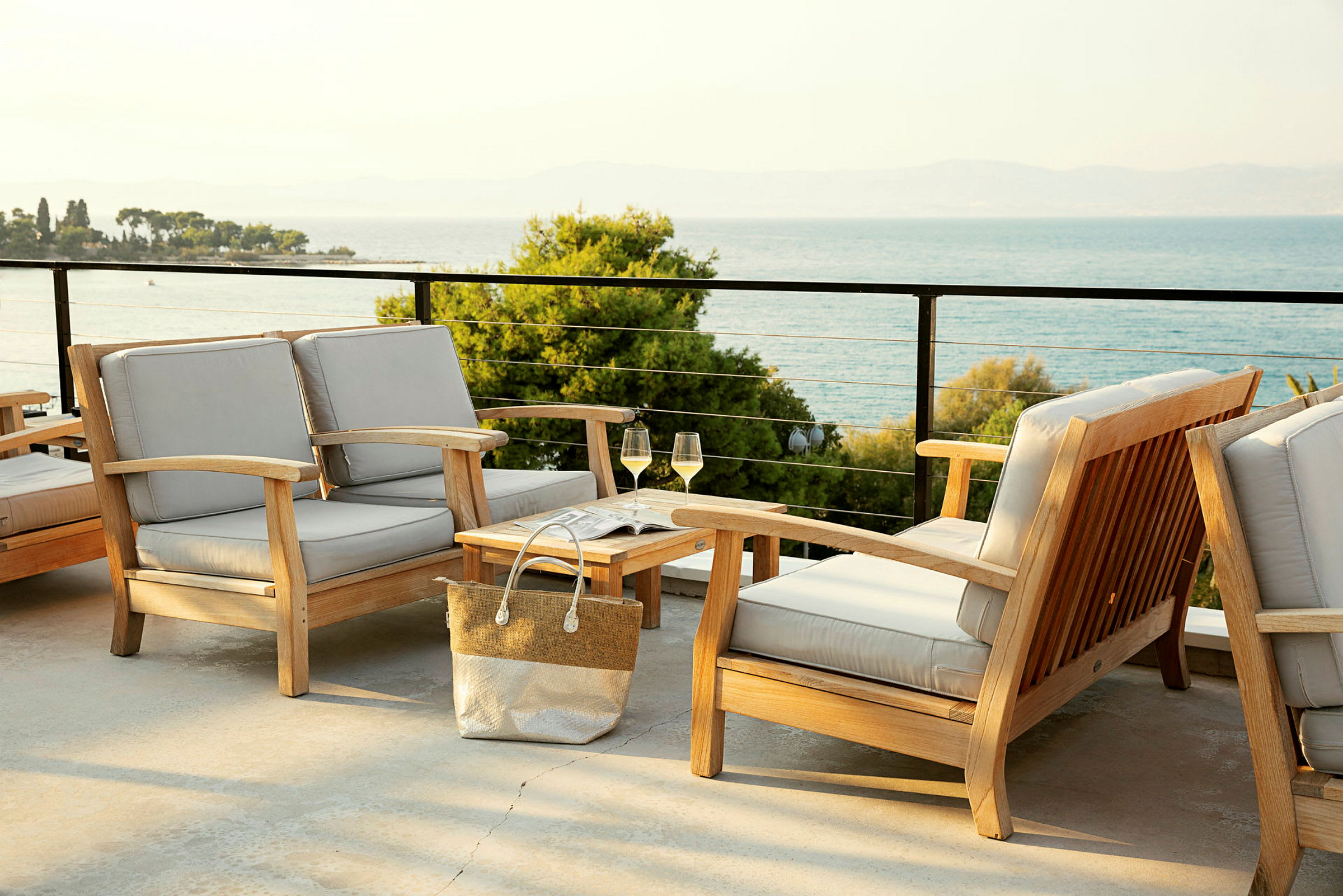 Terrasse med sittegrupper i tre og utsikt over havet. (AI-generert tekst)