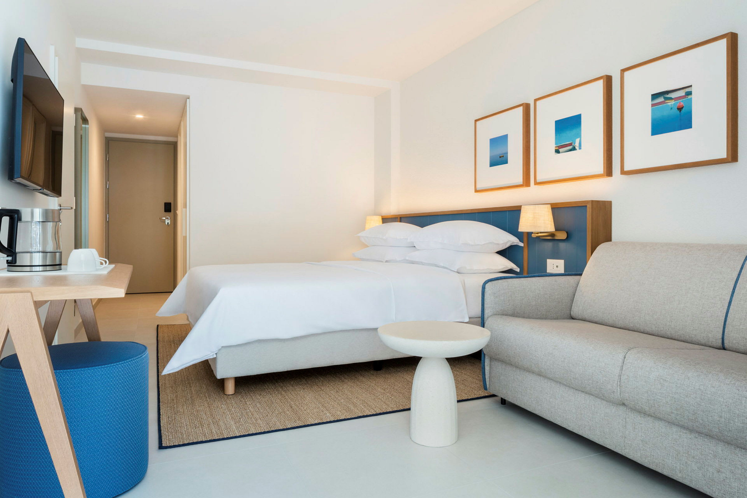 Hotellrom med seng, sofa og bord. (AI-generert tekst)