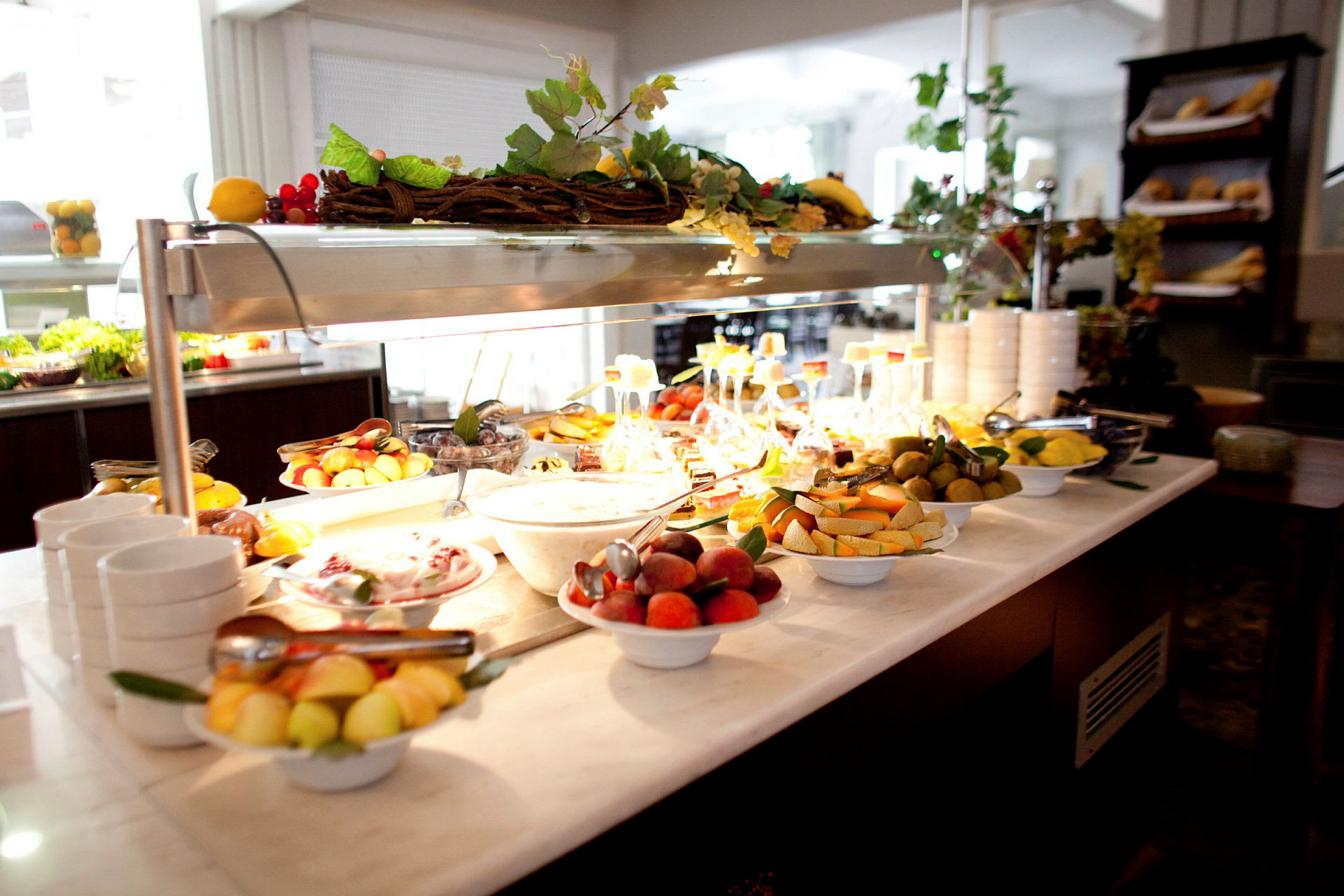 En buffet med fersk frukt og yoghurt i et godt opplyst spiserom. (AI-generert tekst)