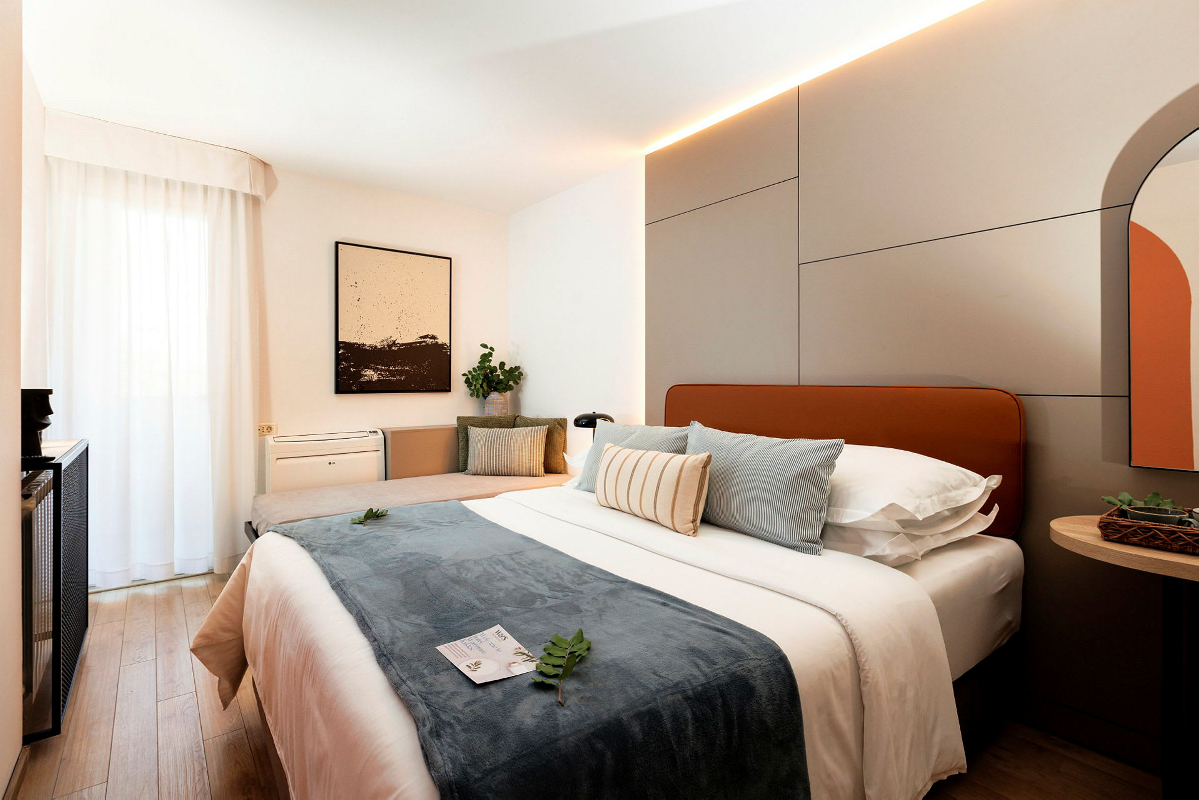 Et moderne hotellrom med en stor seng, puter og interiørdetaljer. (AI-generert tekst)