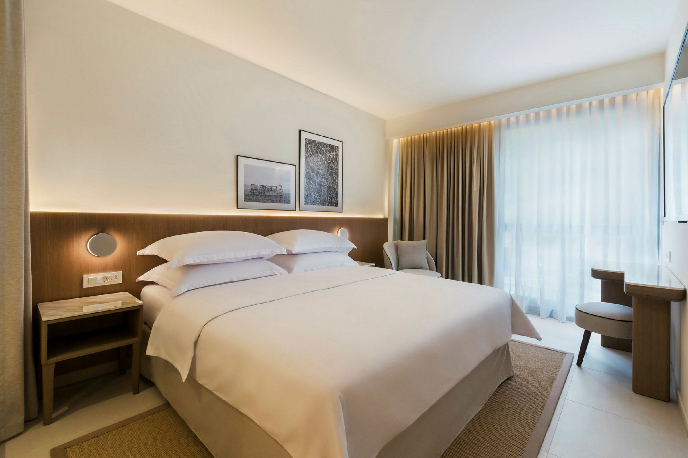 Moderne hotellrom med en stor seng, gardiner og lys innredning. (AI-generert tekst)