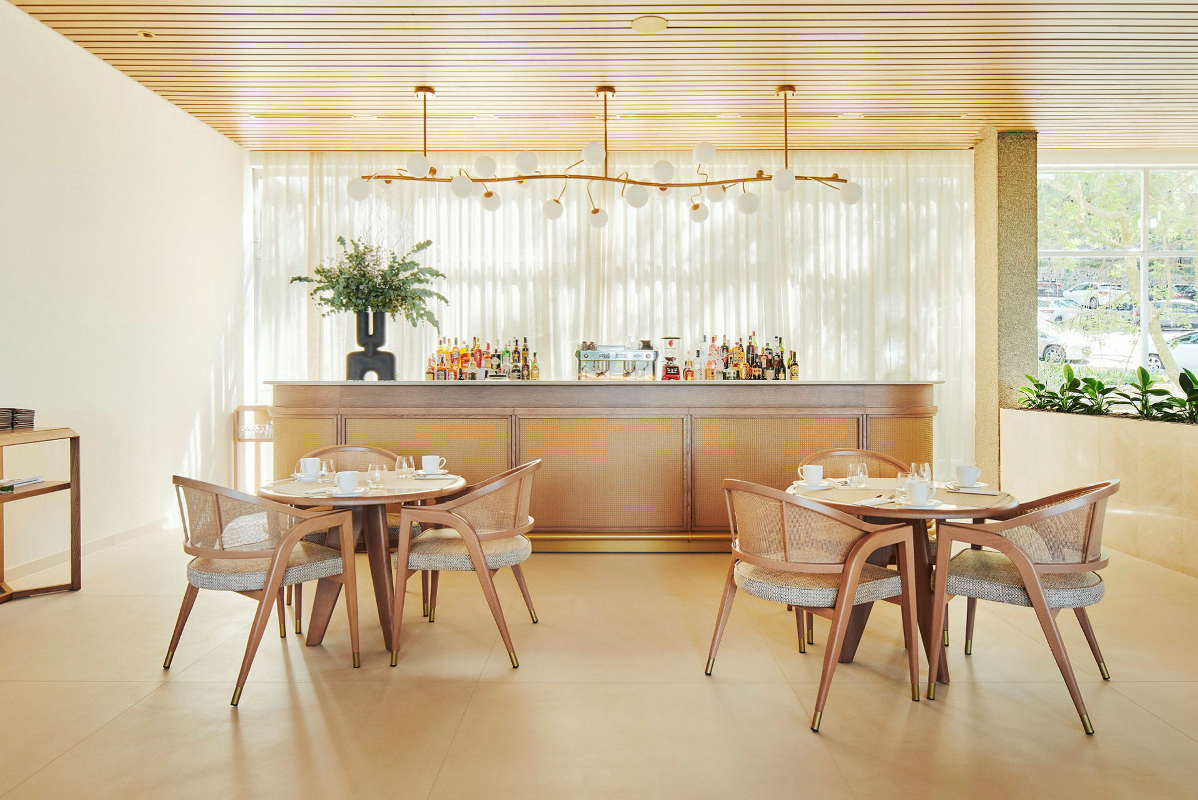 Bilde av en lys restaurantinteriør med trebord, stoler og en bardisk. (AI-generert tekst)