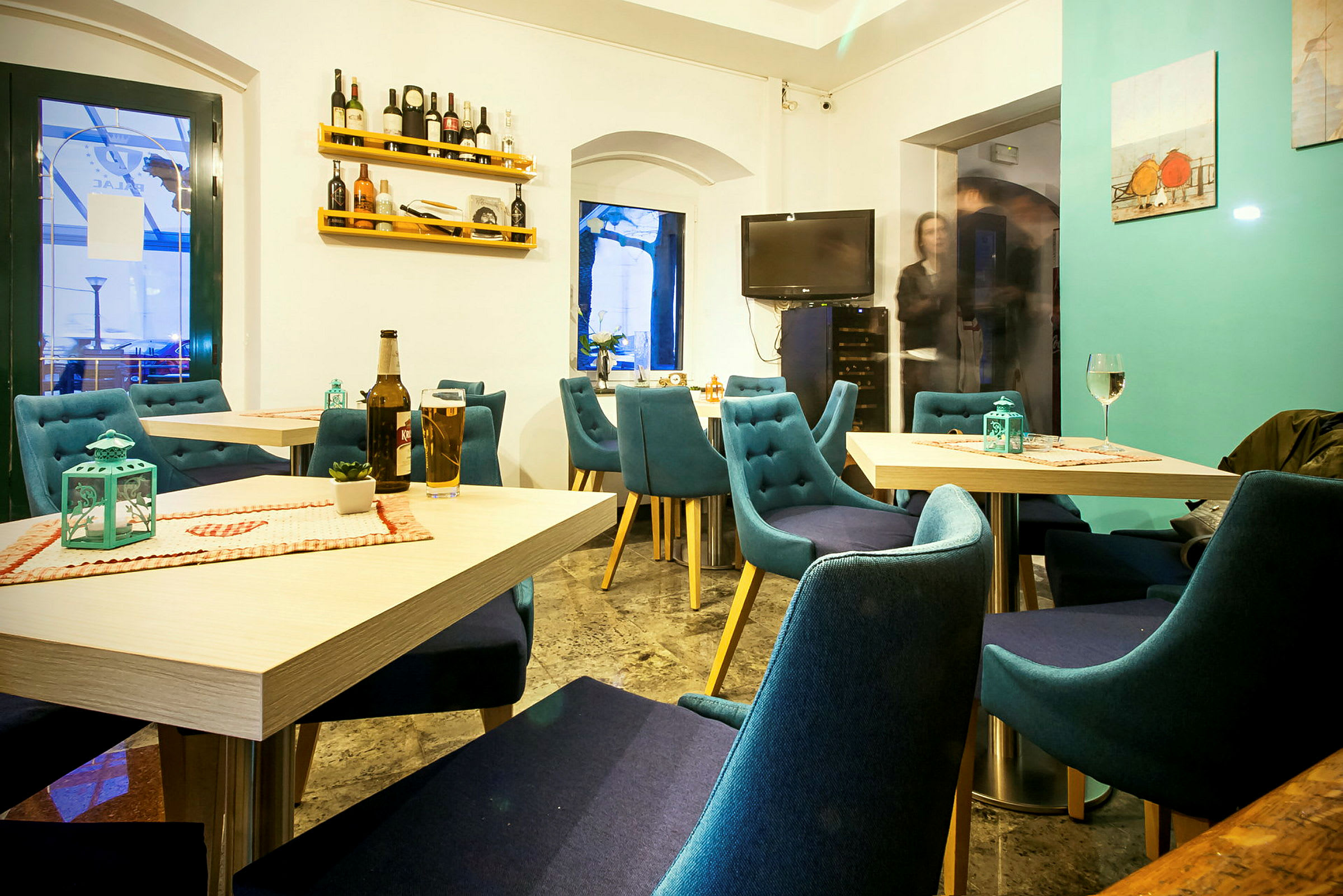 En lys og koselig restaurant med blå stoler og dekkede bord. (AI-generert tekst)