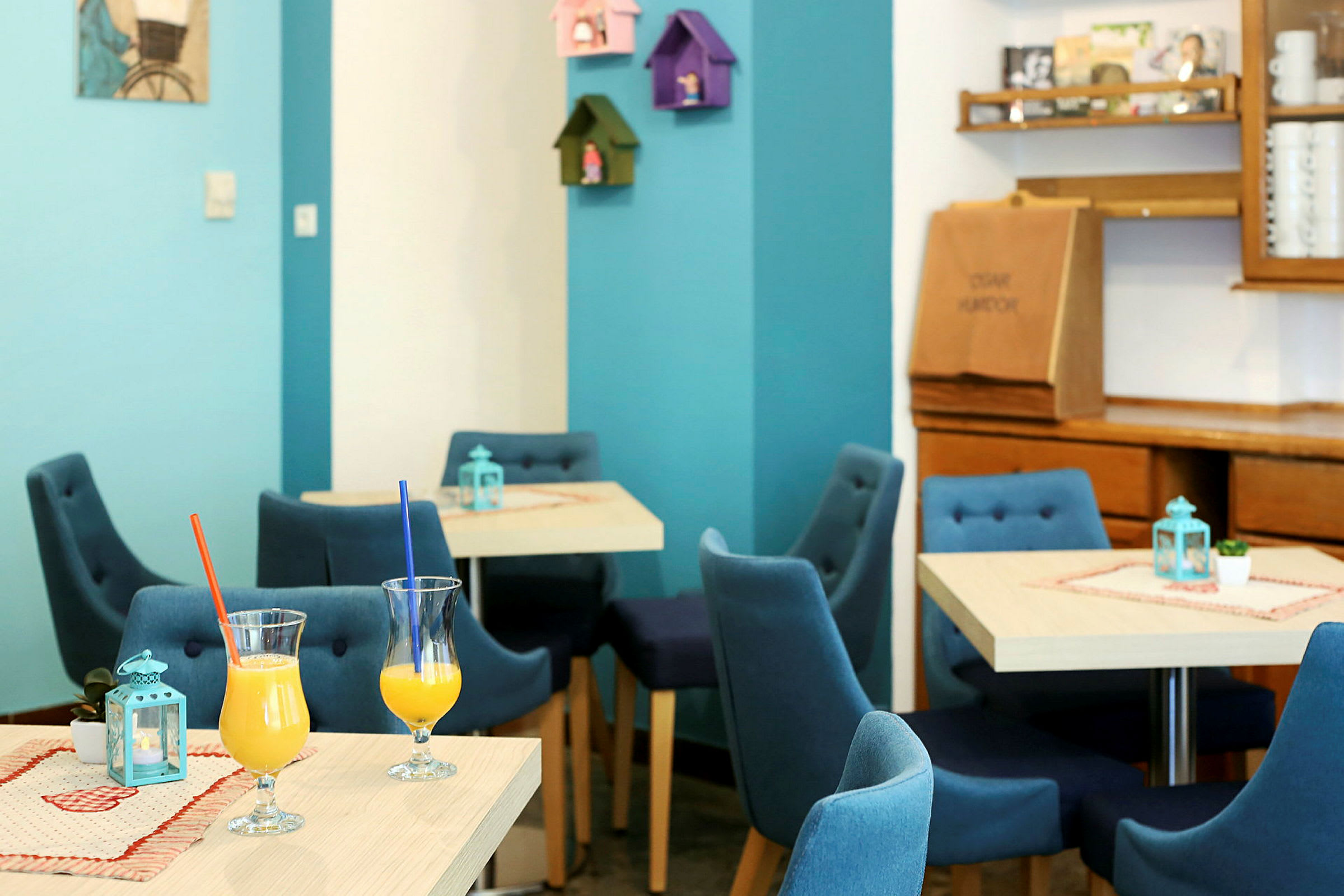 Interiør av en kafé med blå stoler og glass med forfriskende drikker på bordene. (AI-generert tekst)