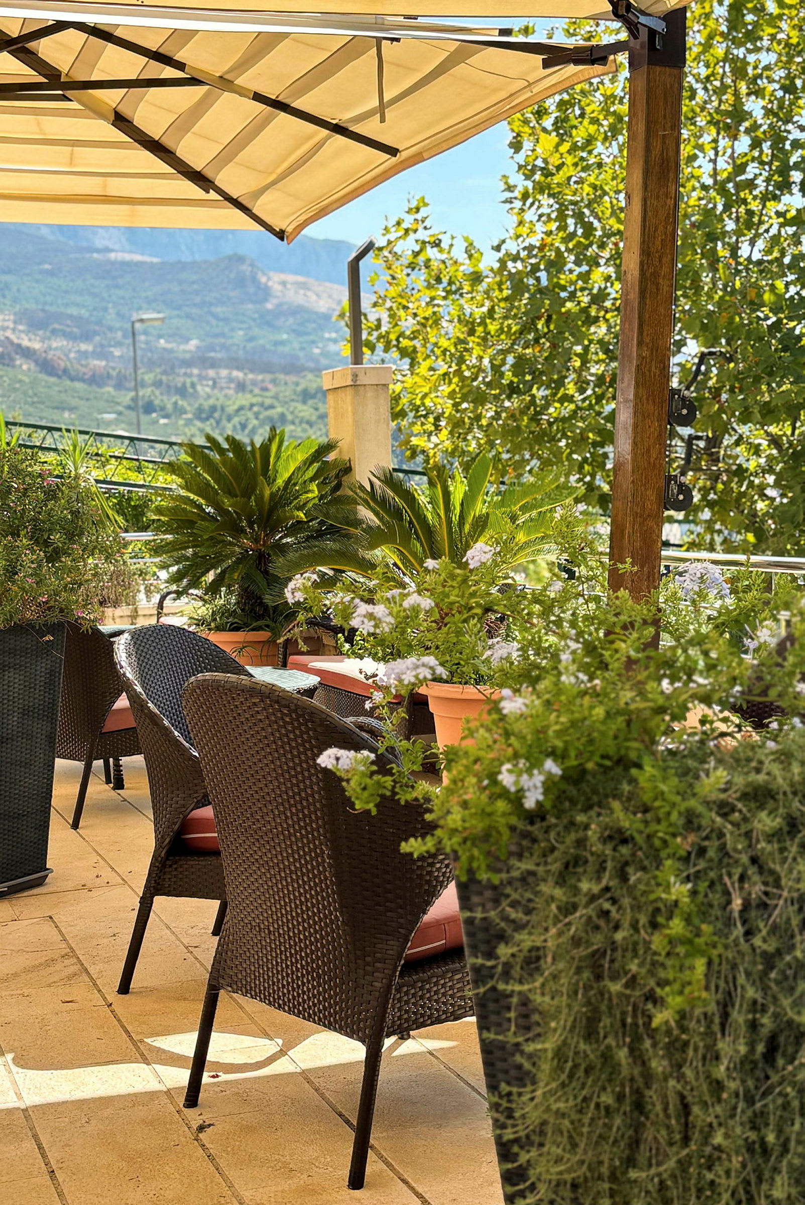 Oppdatert terrasse med stoler, bord og grønt, samt utsikt over et fjellandskap. (AI-generert tekst)