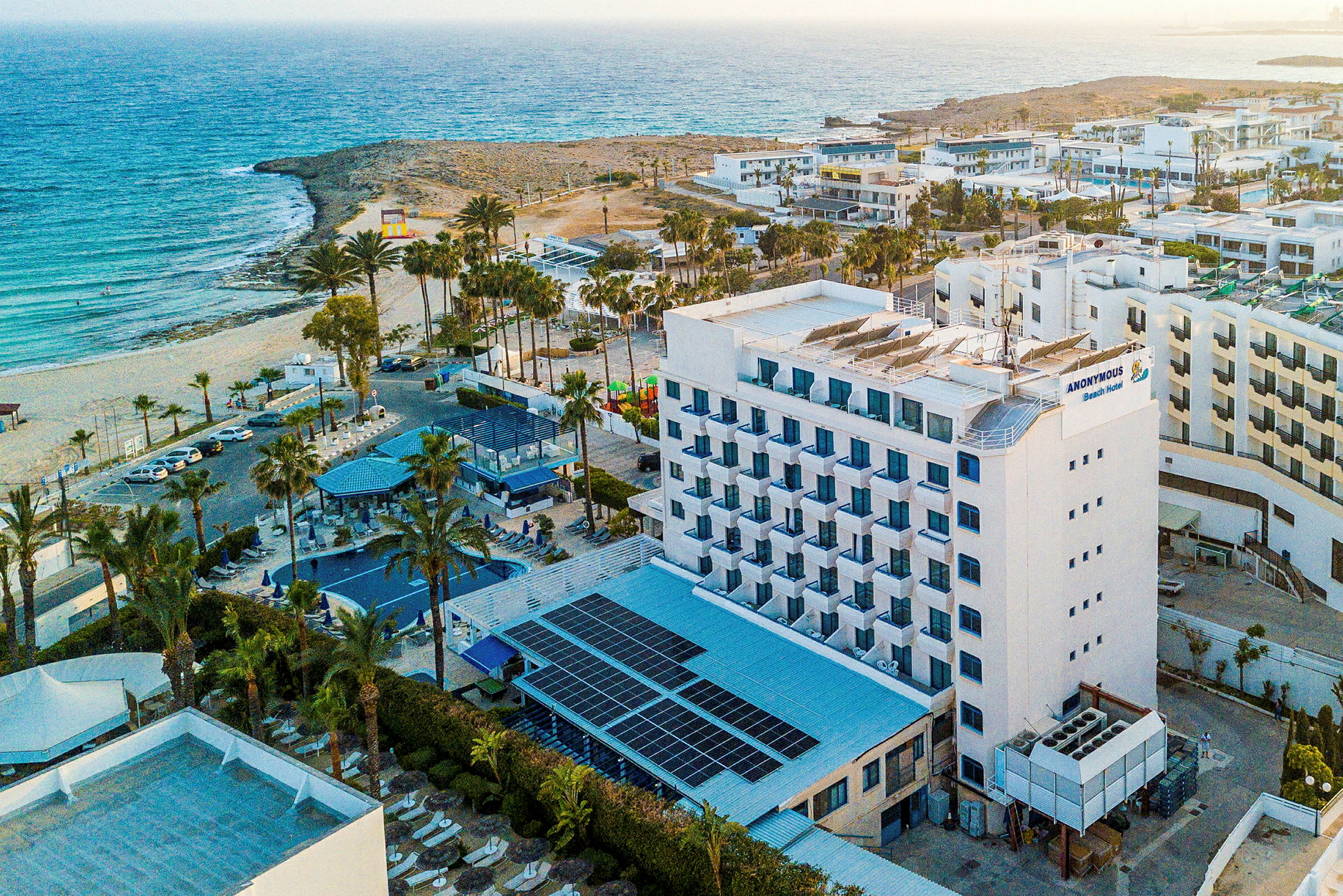 Hotellbygning nær en strand ved havet. (AI-generert tekst)