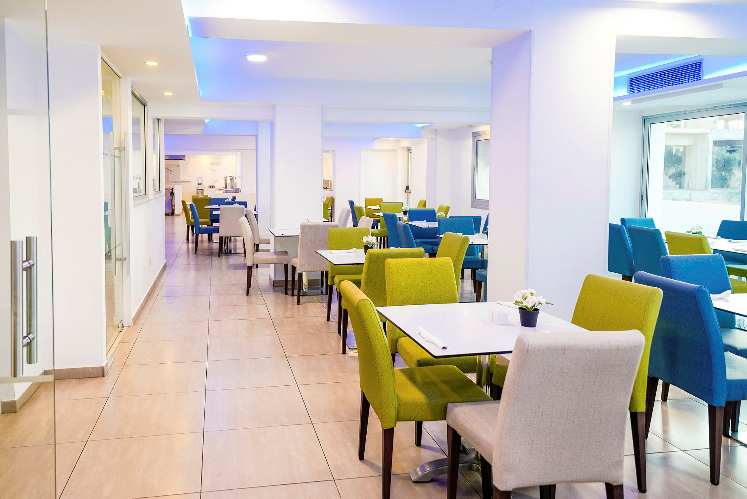Et lyst spisesområde med bord og fargerike sitteplasser. (AI-generert tekst)