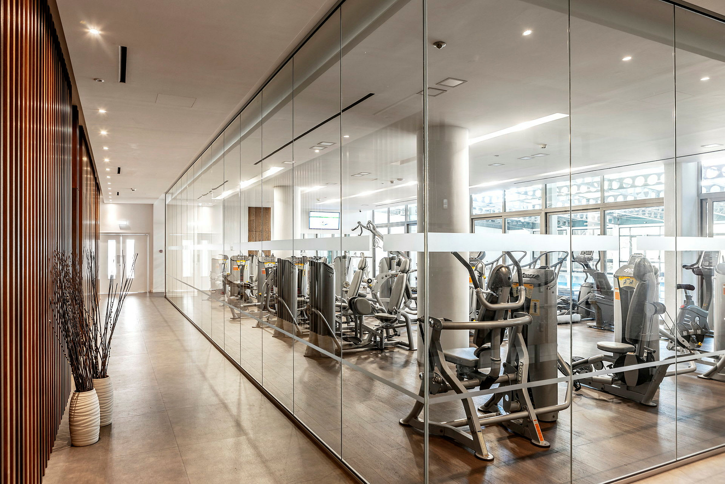 Moderne treningsstudio med treningsmaskiner bak glassvegg. (AI-generert tekst)