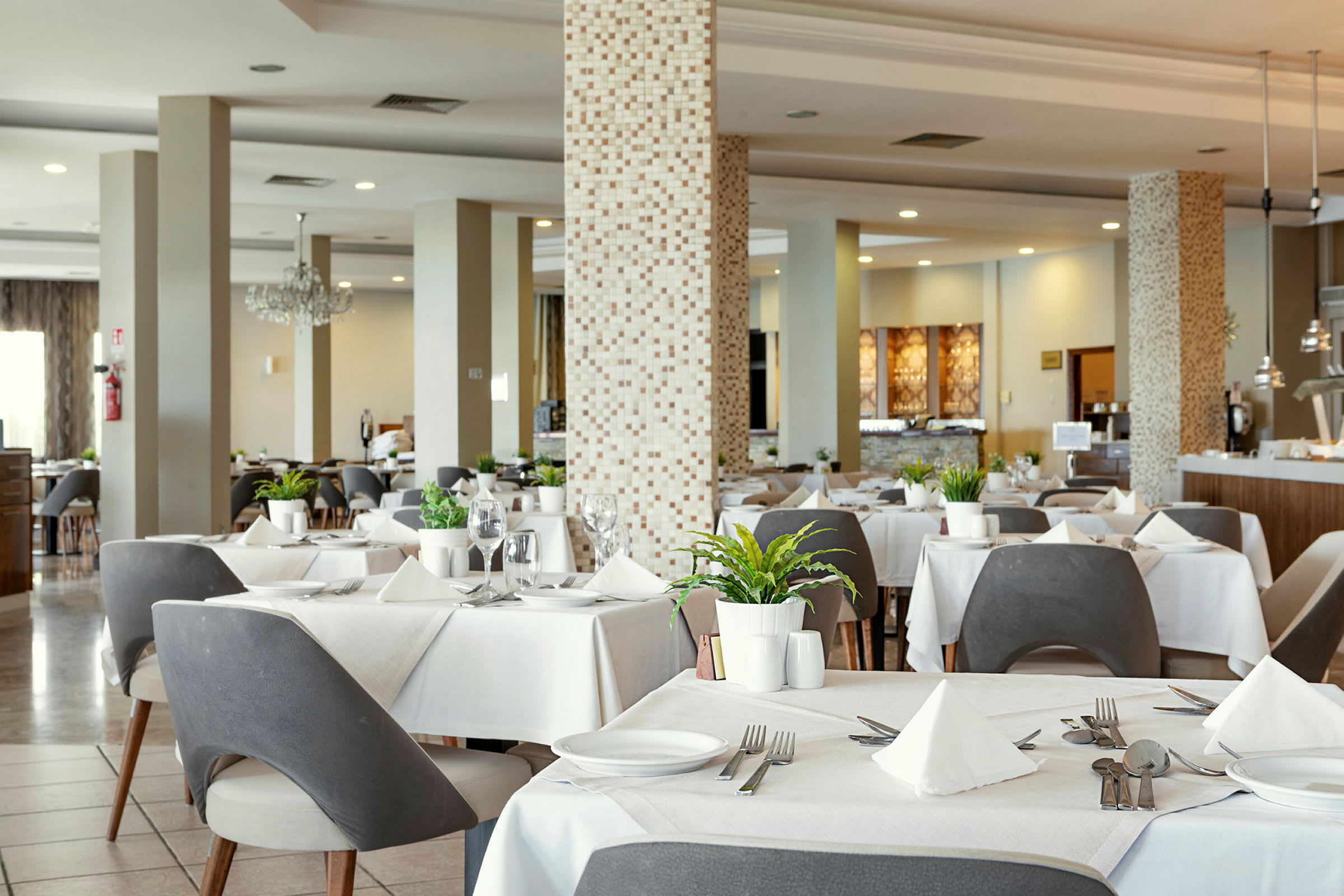 Restaurant med dekkede bord, moderne stoler og dekorasjoner. (AI-generert tekst)