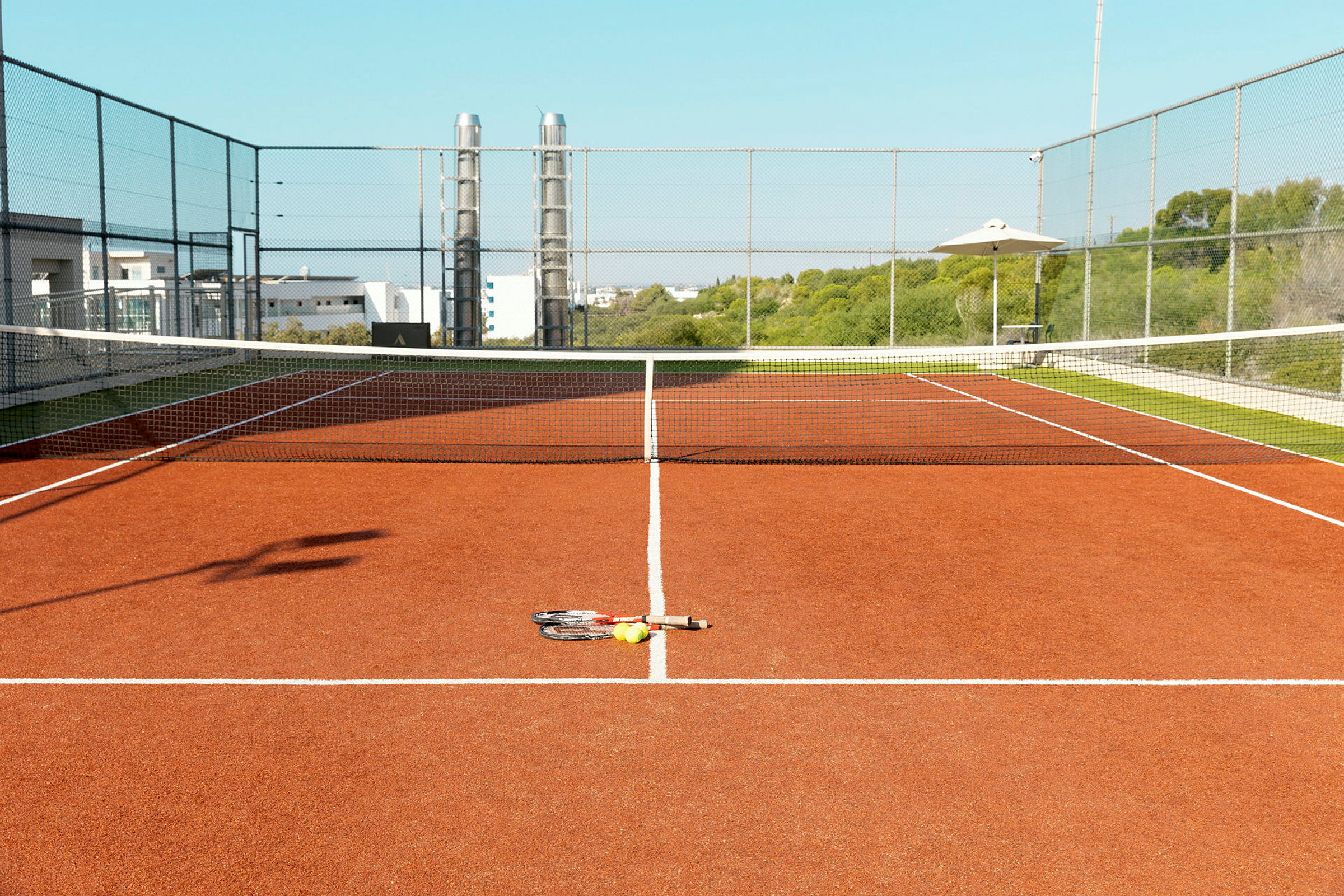 Bilde av en tennisbane med racketer og baller på bakken. (AI-generert tekst)