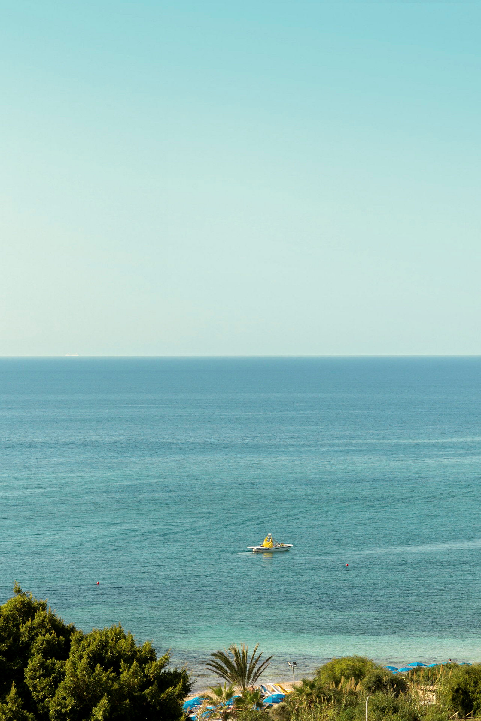 Utsikt over turkist vann med en båt og stranden i forgrunnen. (AI-generert tekst)