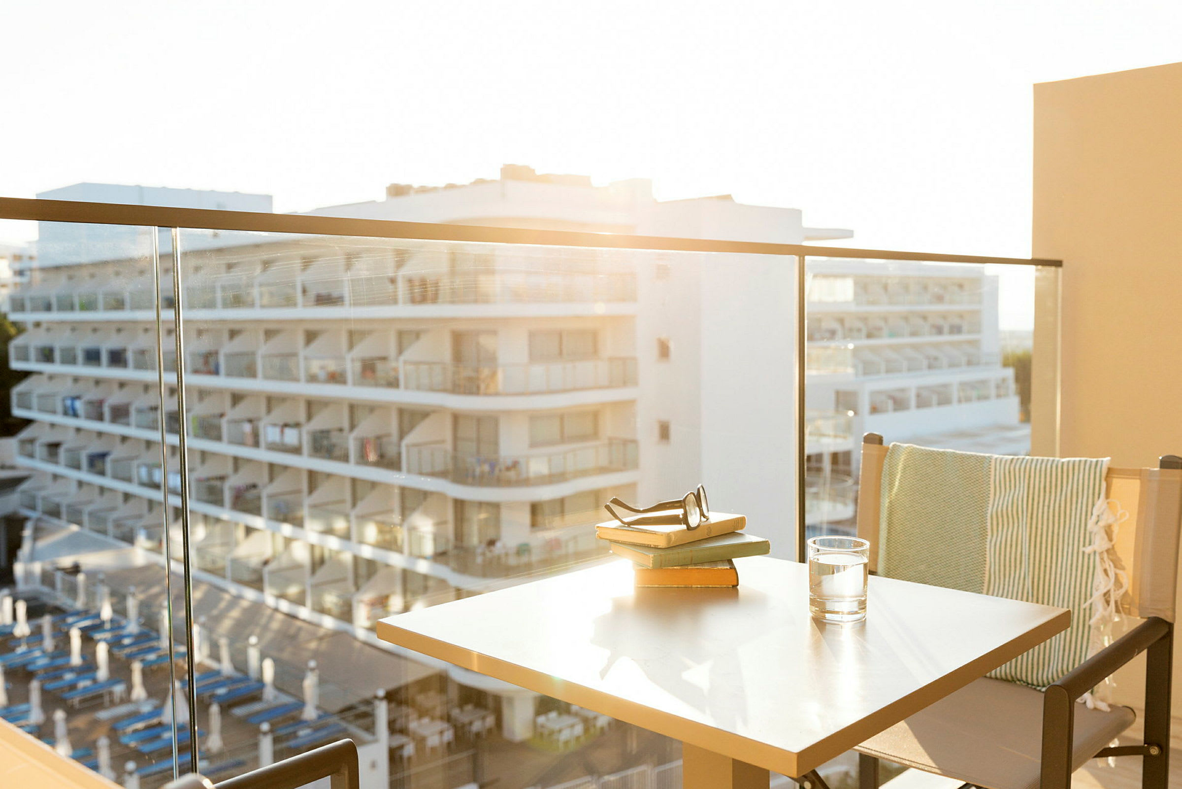 Utsikt fra en balkong med glassrekkverk mot et hotell med balkonger. (AI-generert tekst)