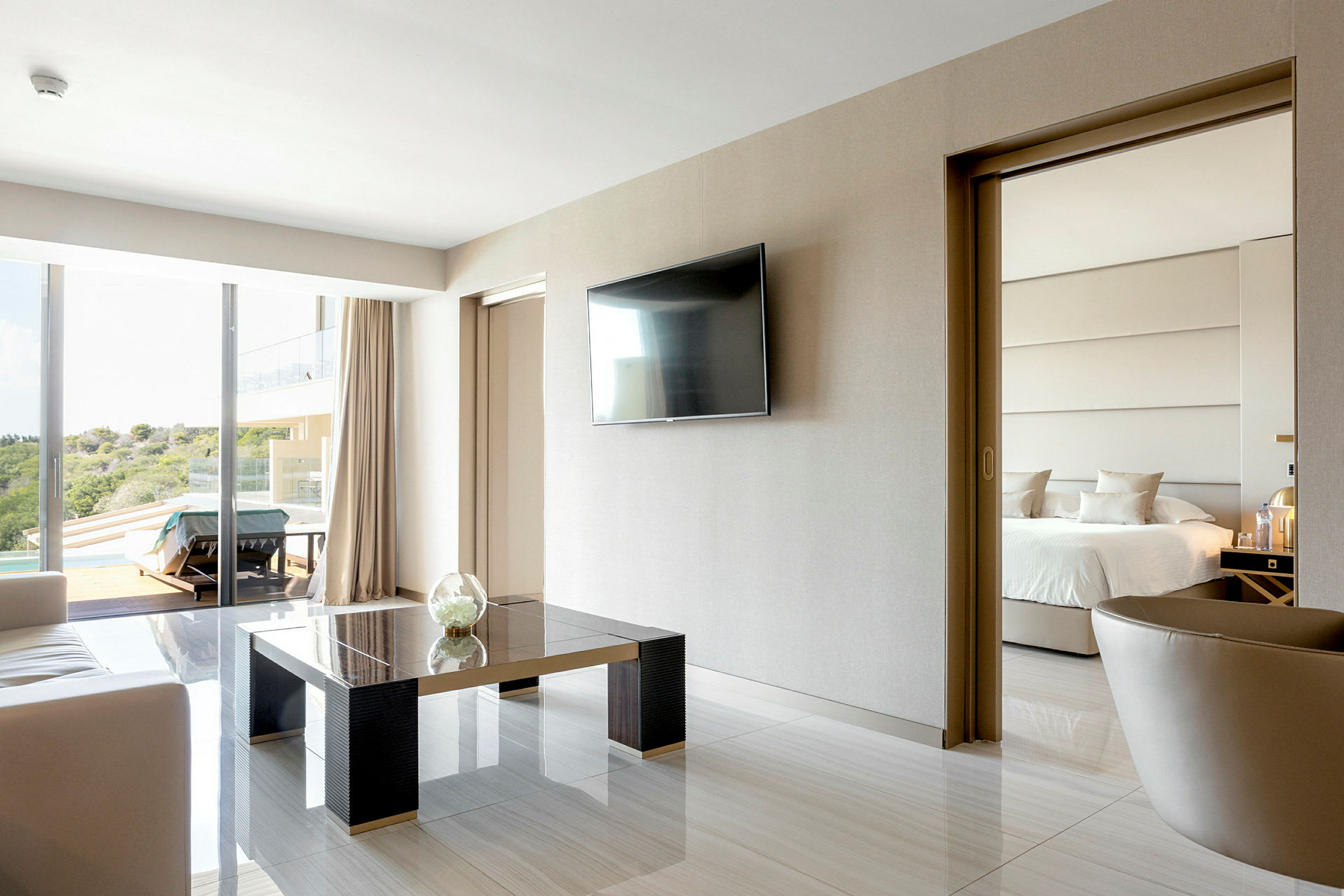 Moderne hotellrom med sitteområde, TV på veggen og skyvedør til soverommet med en dobbeltseng. (AI-generert tekst)
