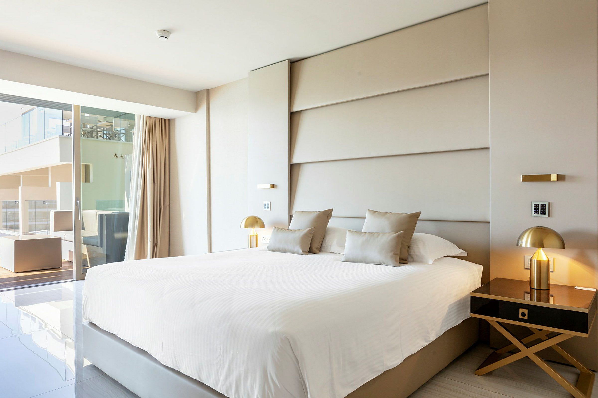 Moderne hotellrom med stor seng, elegant innredning og utsikt mot en terrasse. (AI-generert tekst)