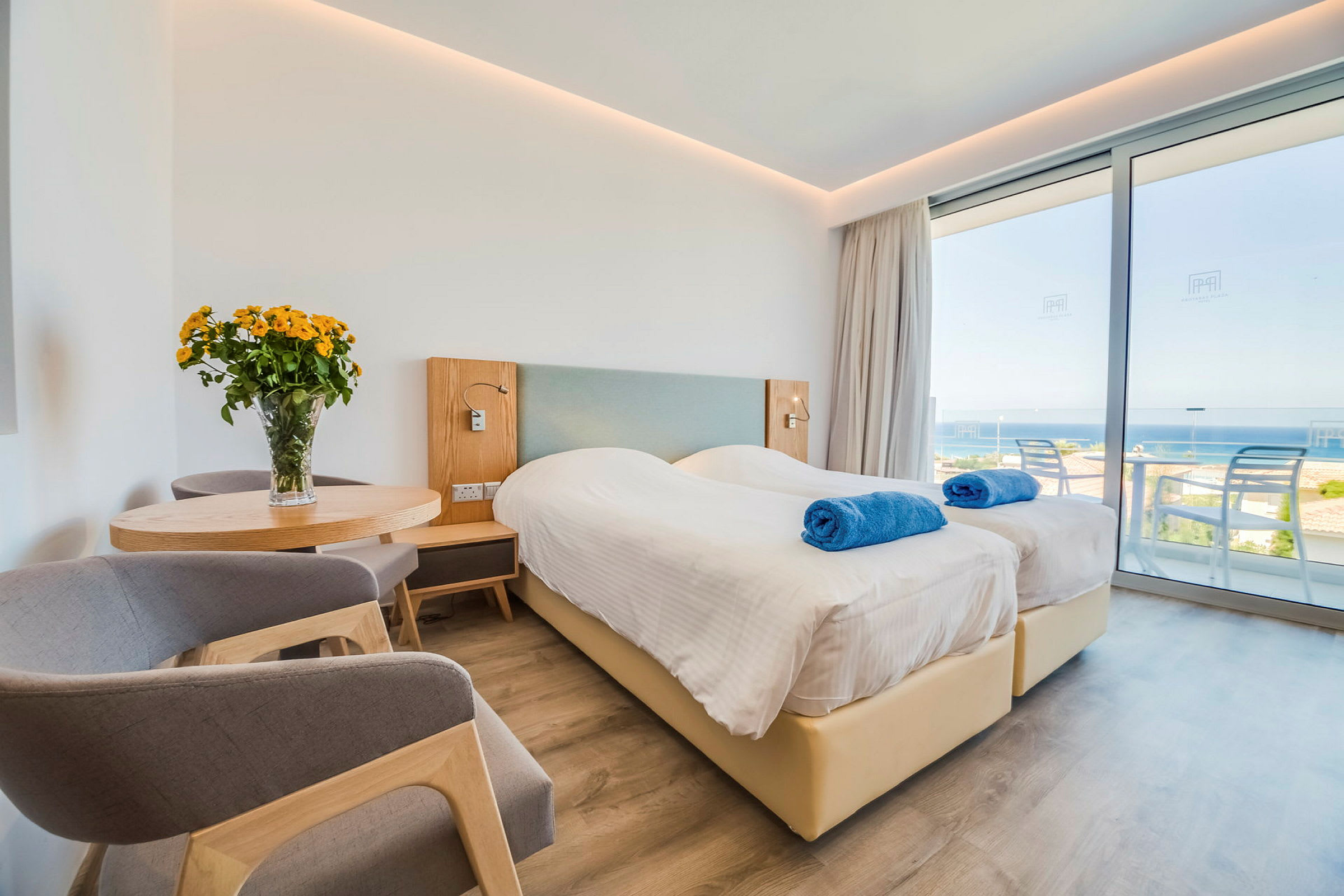 Hotellrom med to enkeltsenger, utsikt over havet. (AI-generert tekst)