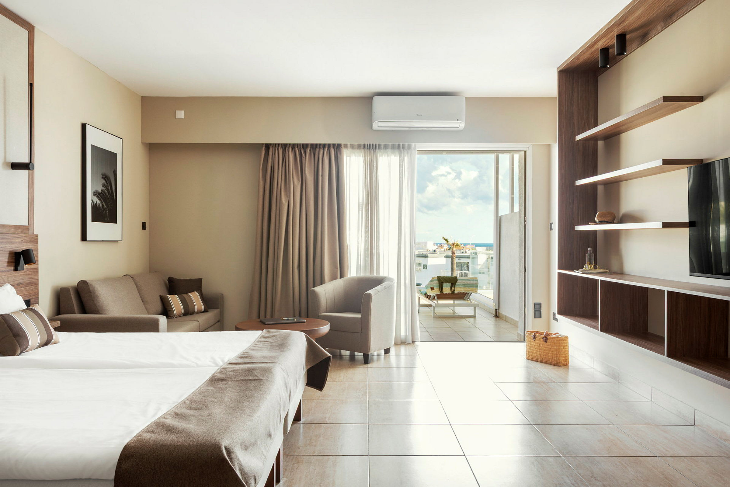 Moderne hotellrom med dobbeltseng, sittemøbler og åpen utsikt fra balkong. (AI-generert tekst)