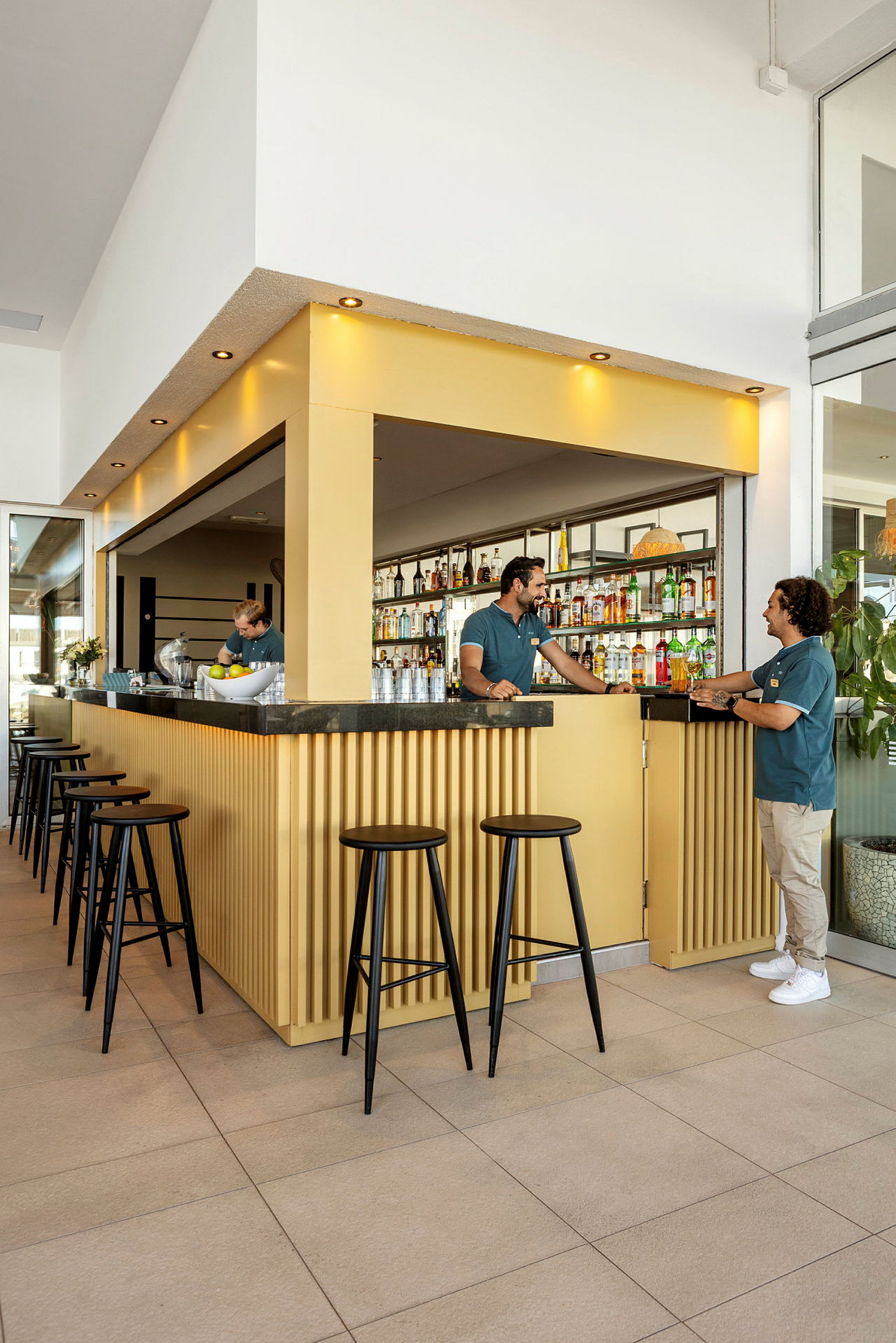 En moderne bar med gul innredning og svarte høye stoler. (AI-generert tekst)