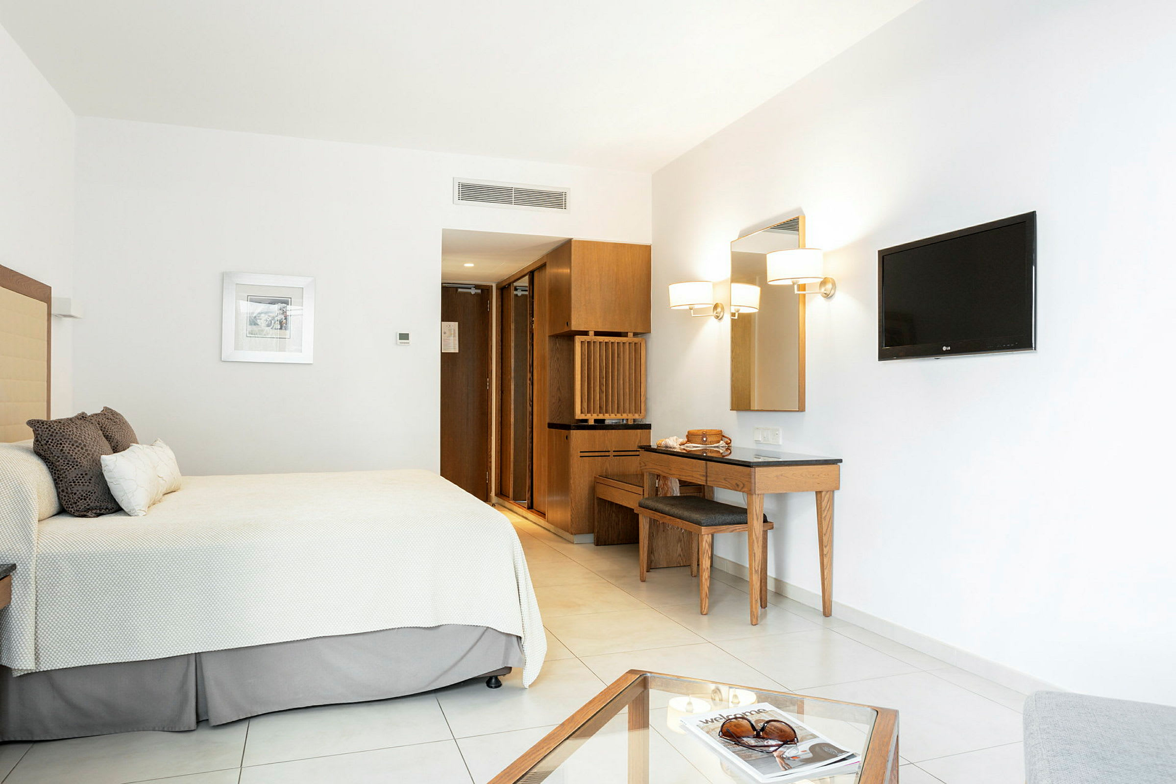 Et minimalistisk hotellrom med seng, veggmontert TV og skrivebord. (AI-generert tekst)