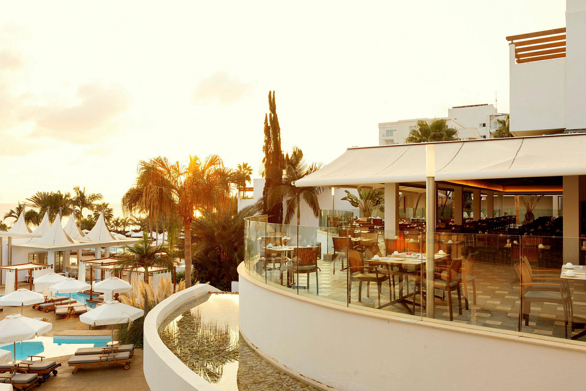 Utendørsområde ved hotell med utsikt over basseng og restaurantområde. (AI-generert tekst)