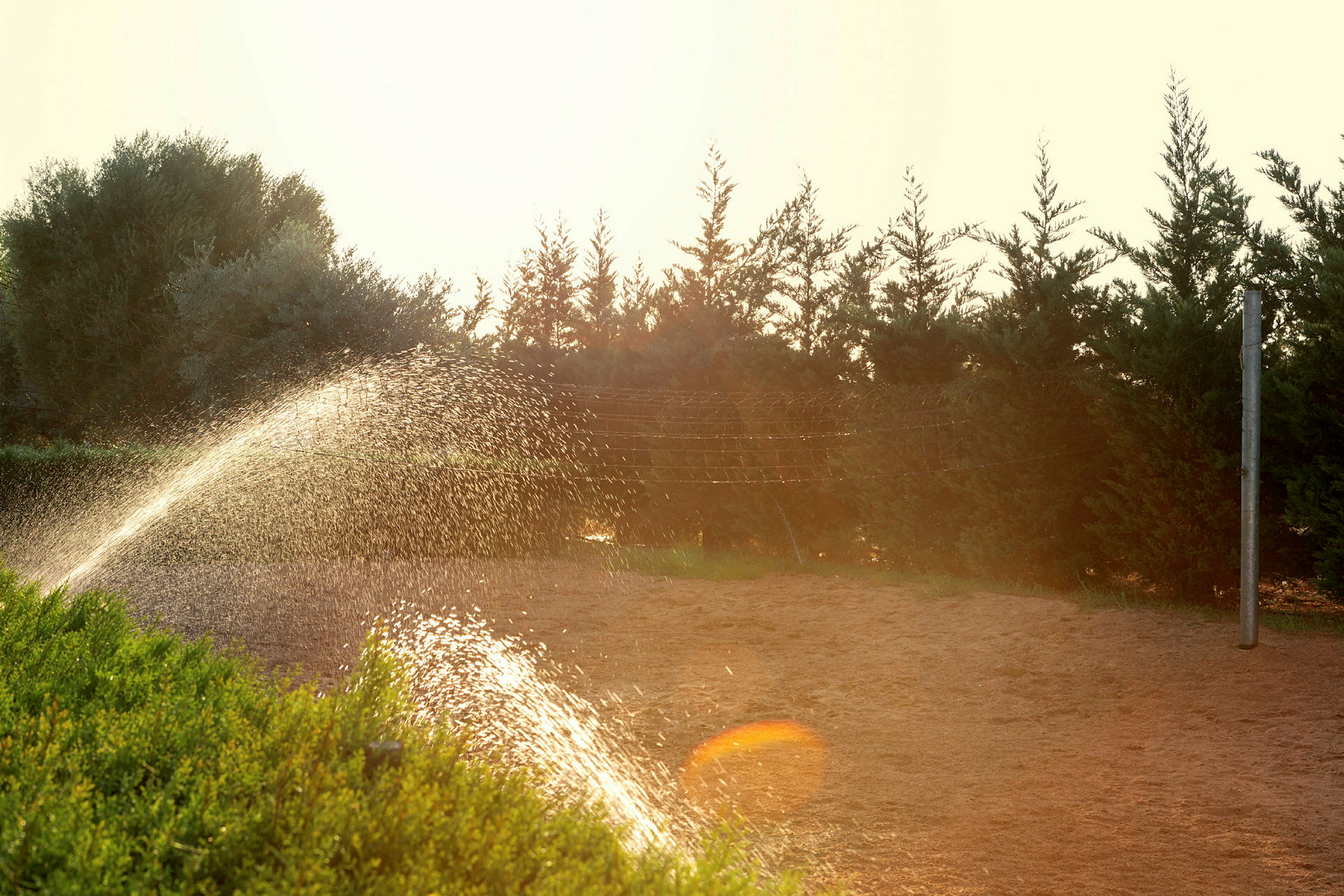 En gård med grøntområder og sprinkler som vanner bakken. (AI-generert tekst)